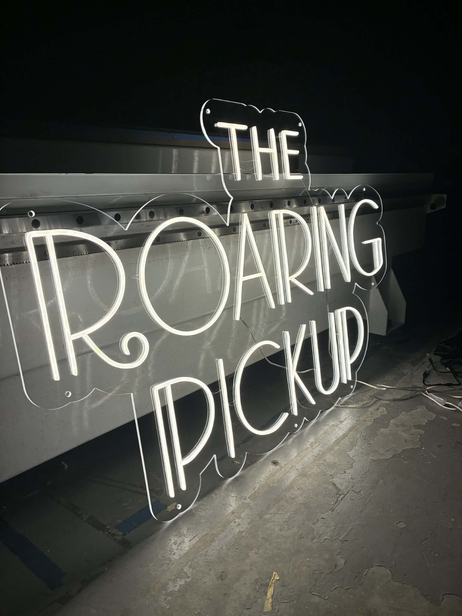 Neon sign reading "THE POD" resting on a metal surface in a dark room.