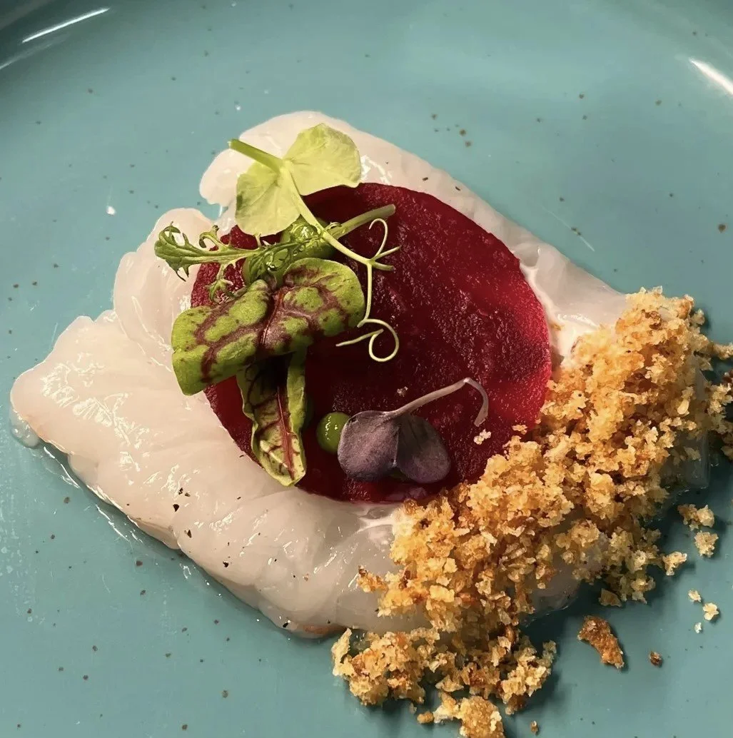Piatti di pesce con caviale, avocado, erbe aromatiche e pane croccante su un piatto blu.