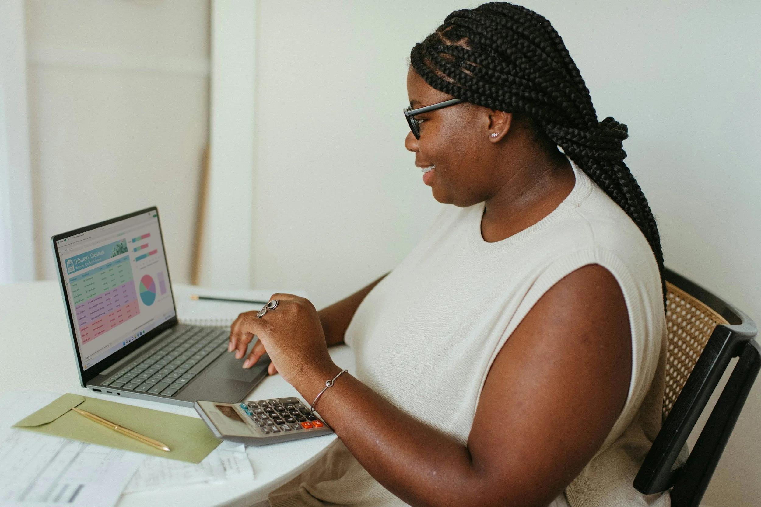 A black woman wearing a cream top looking at financial charts on a laptop