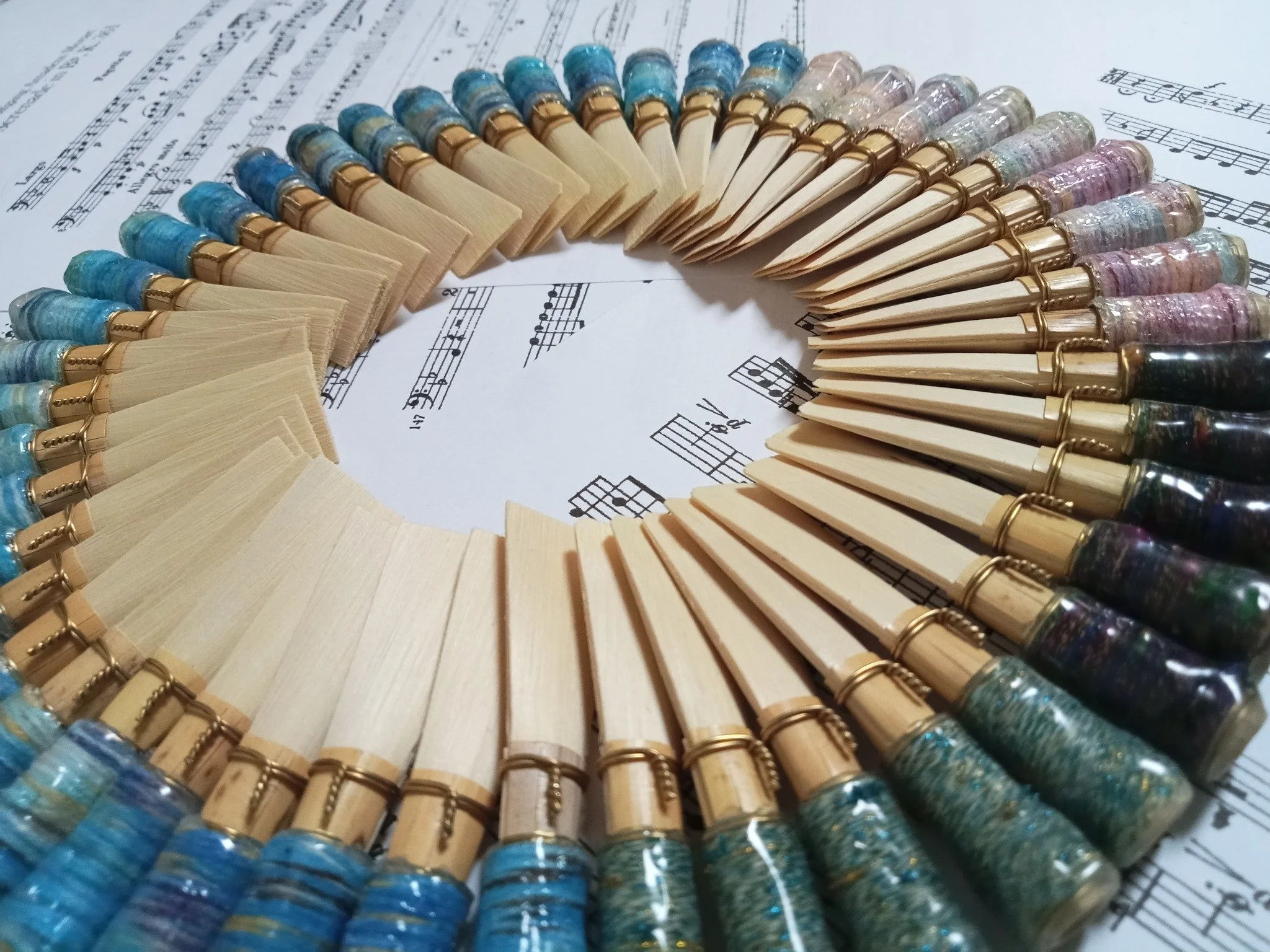 Colored pencils arranged in a circular pattern on sheet music.