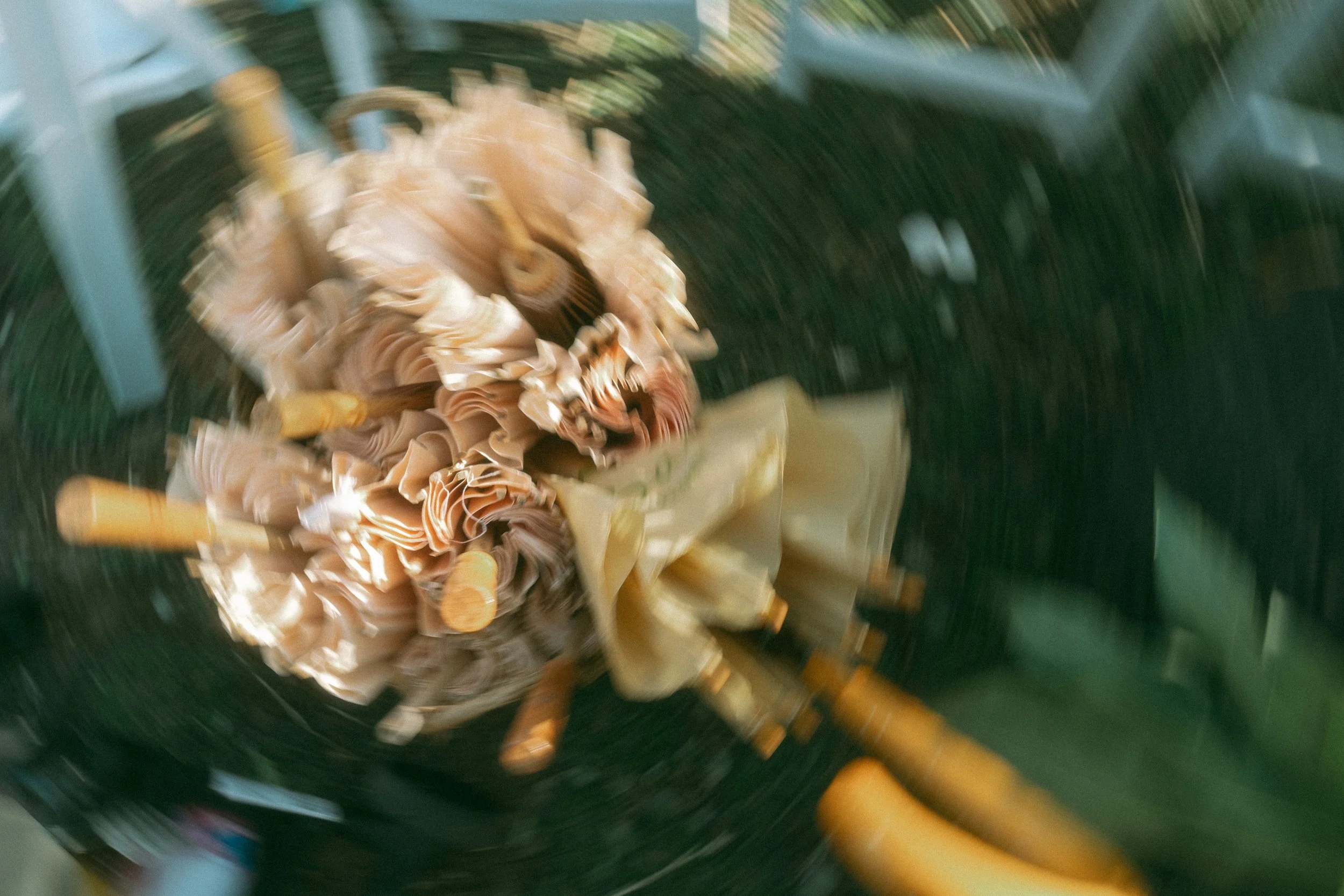 Blurred image of a decorative floral centerpiece on a table, surrounded by various objects, with a dark, possibly black, background.