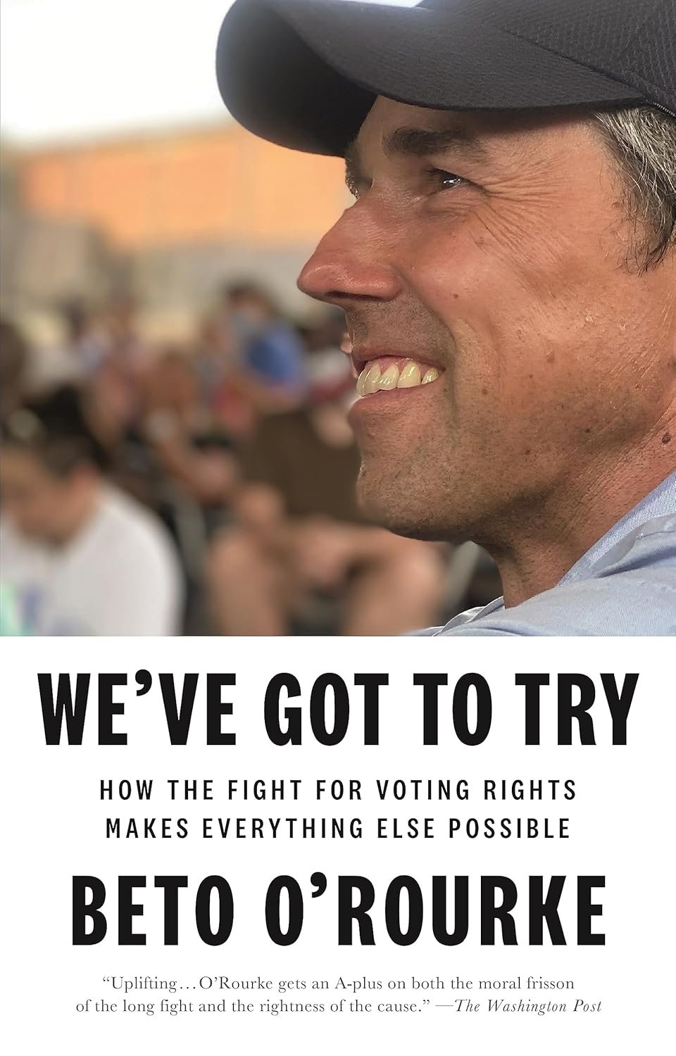 A man with a hat smiling, with a blurred group of people in the background, and a headline about voting rights featuring Beto O'Rourke.