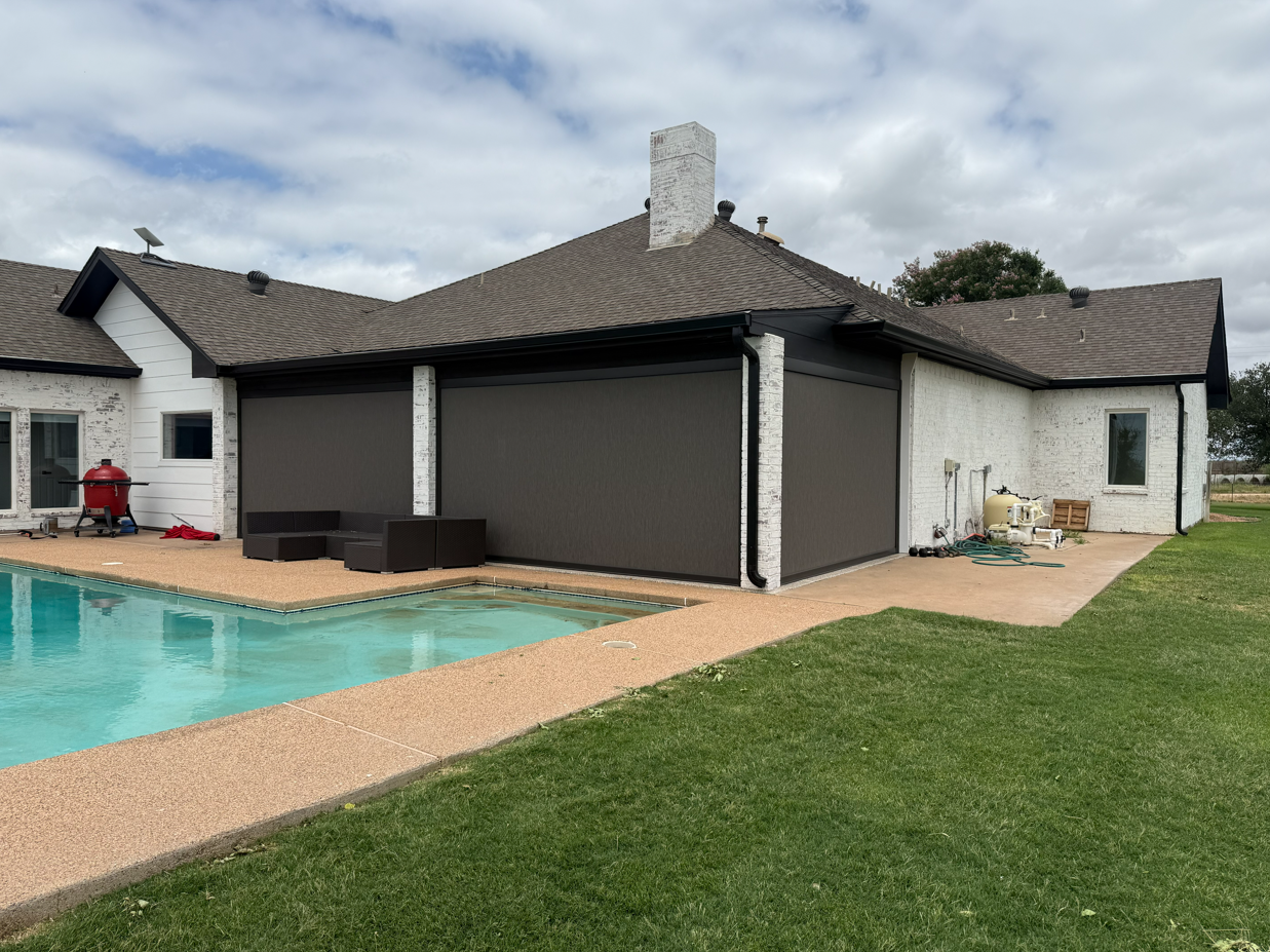 Backyard with a swimming pool, patio furniture, and a house with a screened-in pool enclosure, cloudy sky, and maintained lawn.