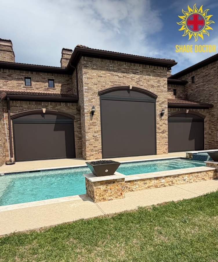 A backyard with a rectangular pool, brick house exterior, and three large black window shades. There are two black outdoor wall lanterns, a small grassy area in the foreground, and a cloudy sky. The logo and text 'Shade Doctor' appear in the top right corner.