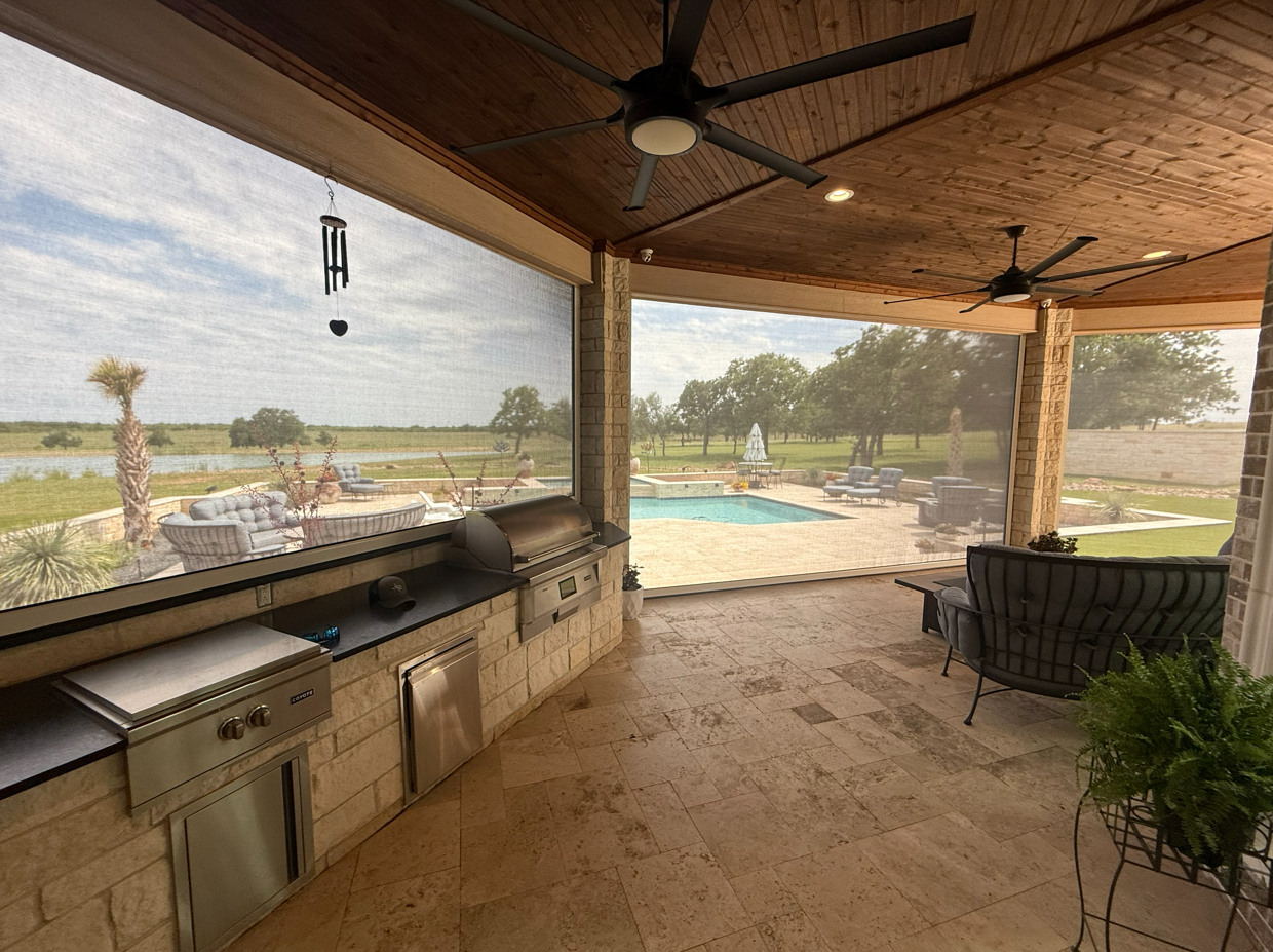 Covered patio with ceiling fans overlooking a backyard with a swimming pool, lounge chairs, and a grassy yard with trees.