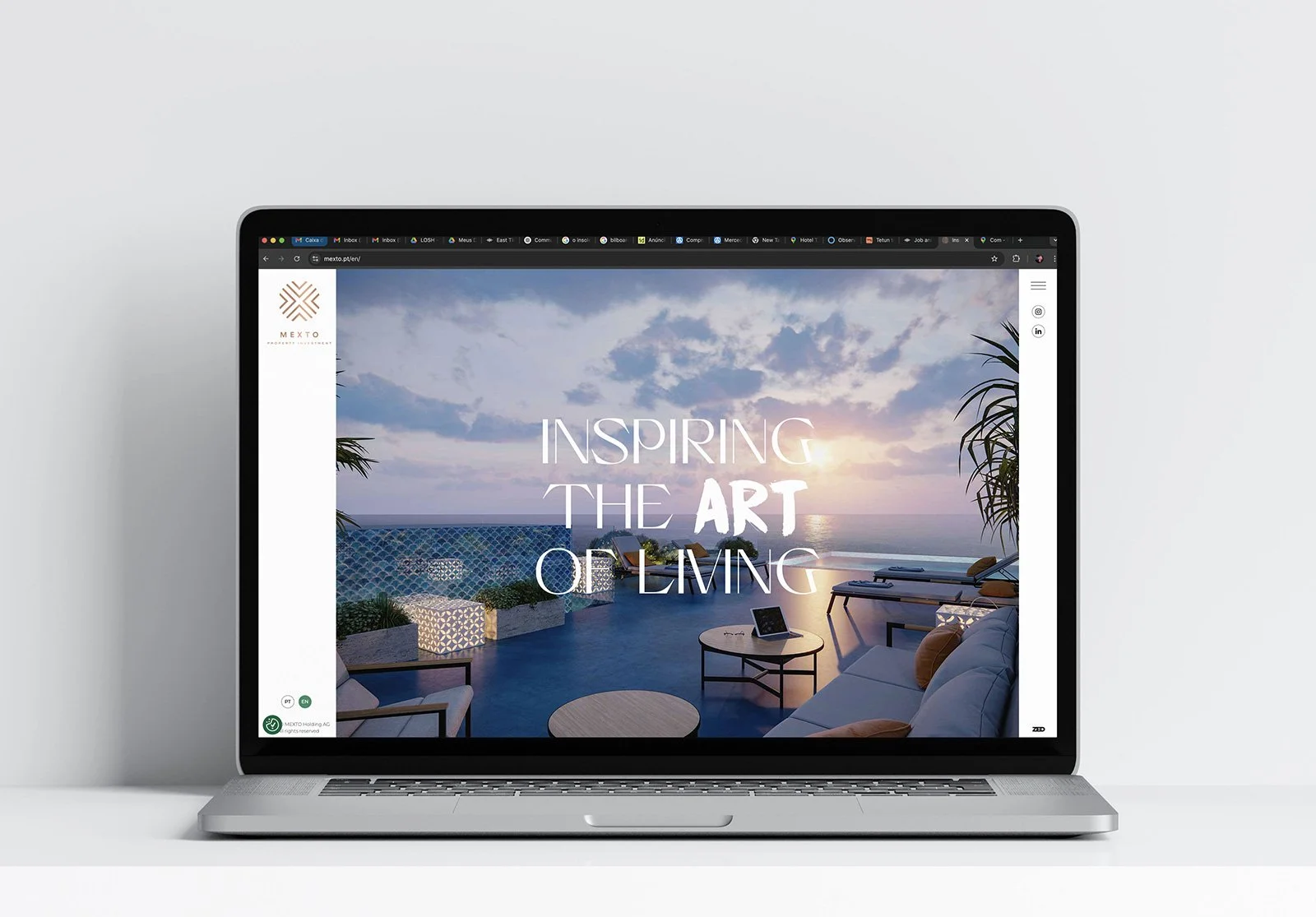 Laptop displaying a website with an outdoor terrace view at sunset, with the text 'Inspiring the Art of Living' overlaid.