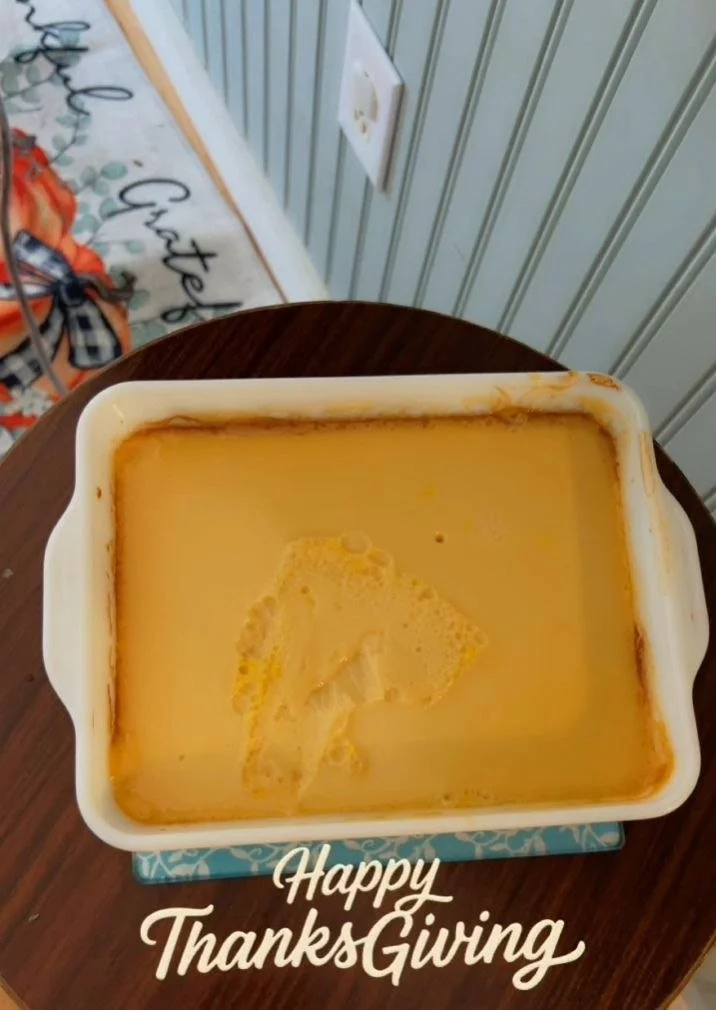 A tray of mashed sweet potatoes on a wooden table, with the words "Happy Thanksgiving" overlayed at the bottom.