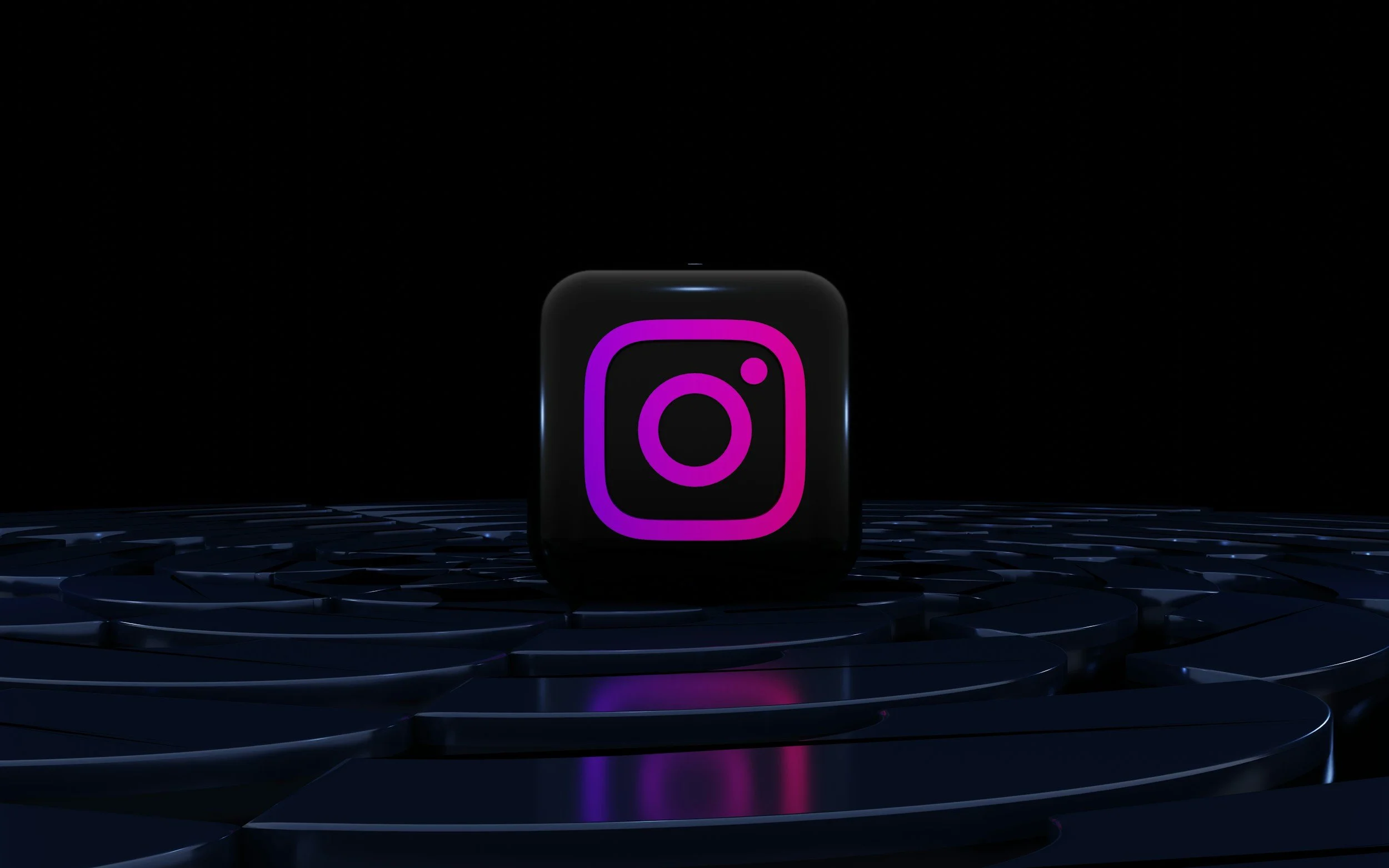 A digital display of the Instagram logo illuminated in pink and purple colors, set against a dark background with reflective surfaces on which the logo is placed.