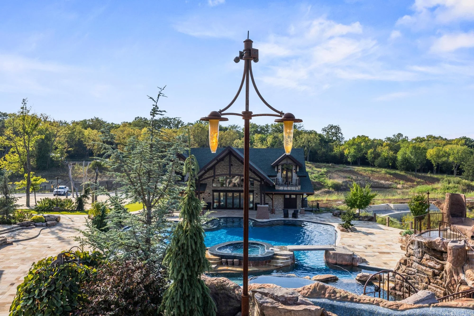 Outdoor pool area with a house, trees, and a clear blue sky.
