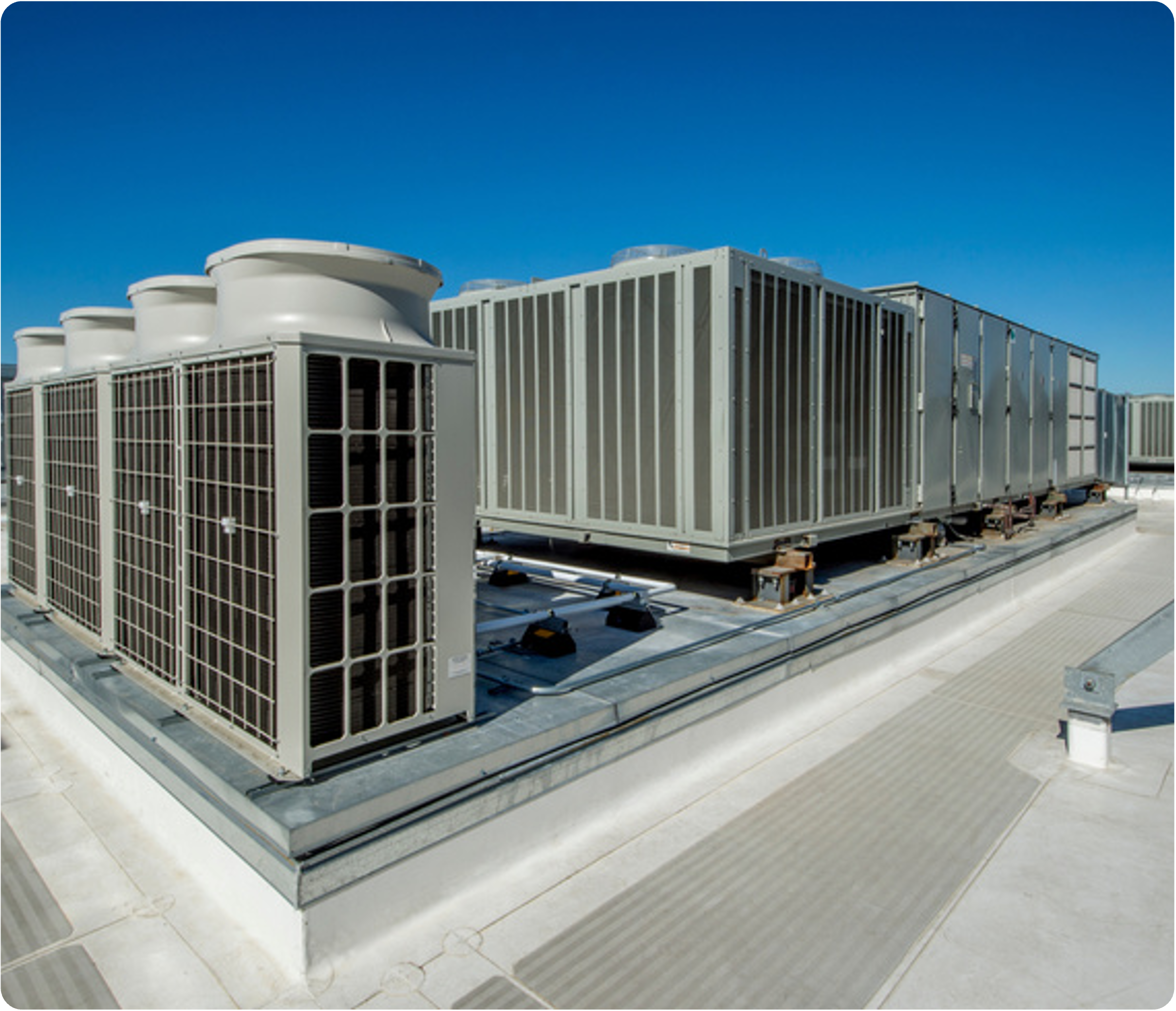 Large rooftop HVAC Units on a flat rooftop under a clear blue sky with tiled flooring.