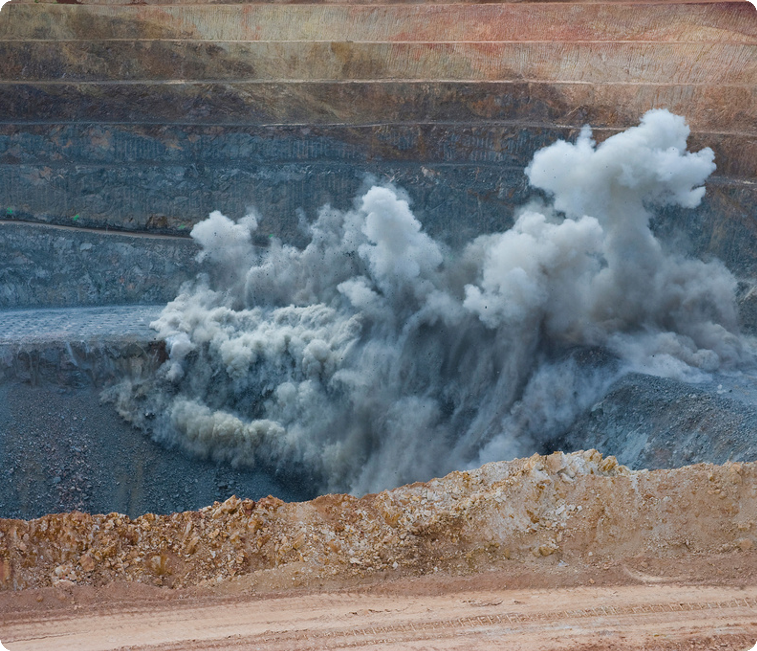 An image of a rock quarry where explosives have just been detonated leaving a cloud of smoke.