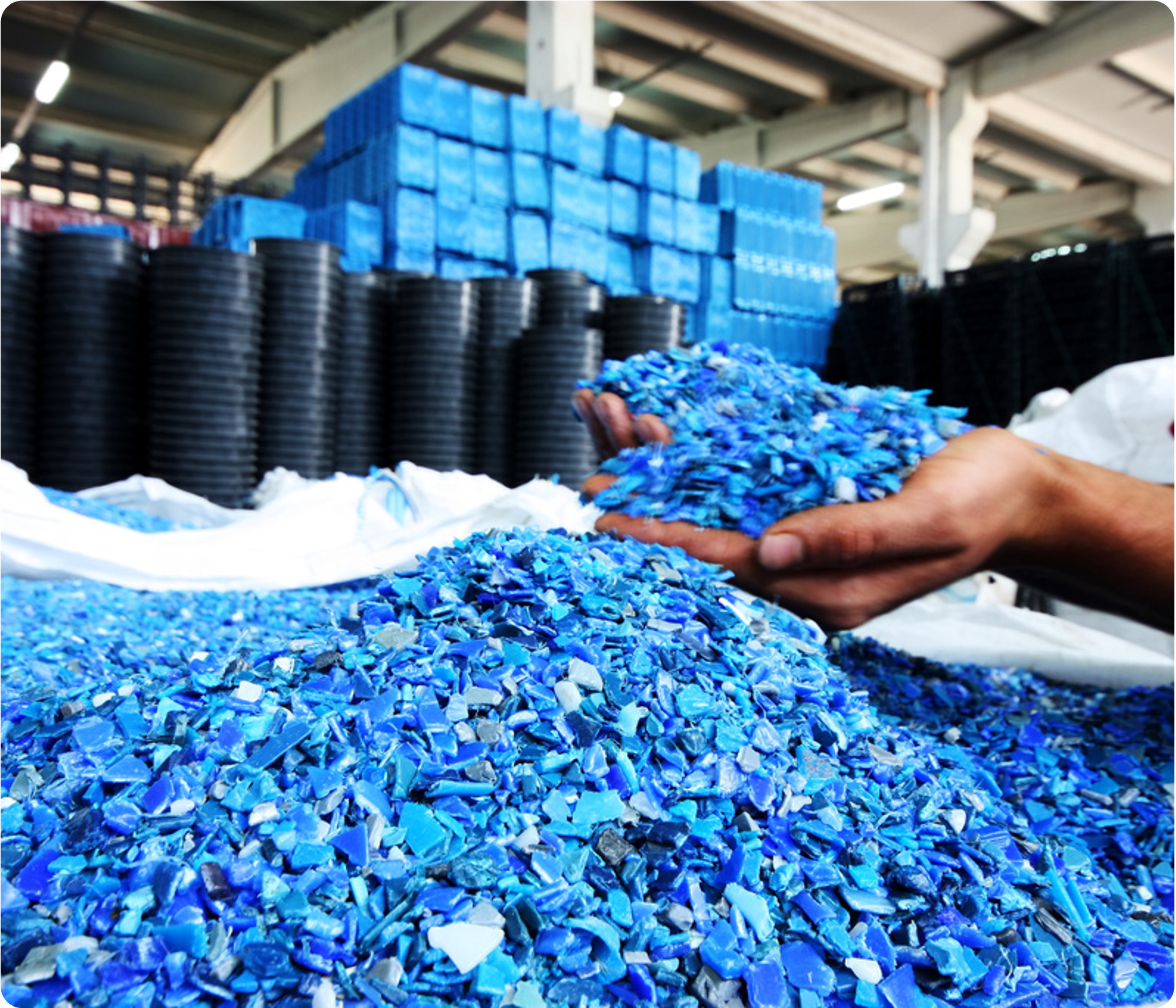 Blue plastic fragments in a warehouse setting with stacked blue containers in the background.