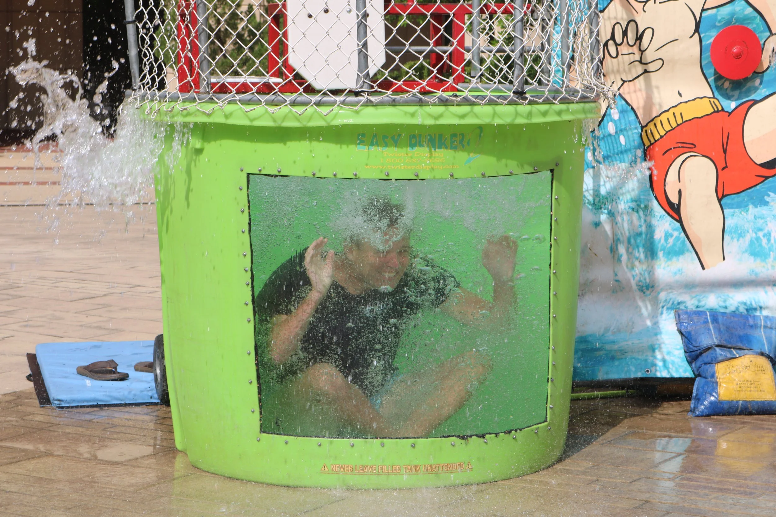 Columbia, SC mayor in a water-filled splash tank at an event. The tank is green with a clear front window.