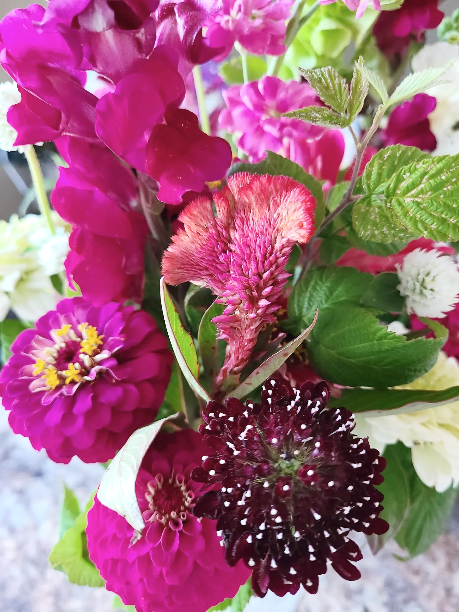 A vibrant bouquet of various colorful flowers including pink, purple, red, and white blossoms with green leaves.