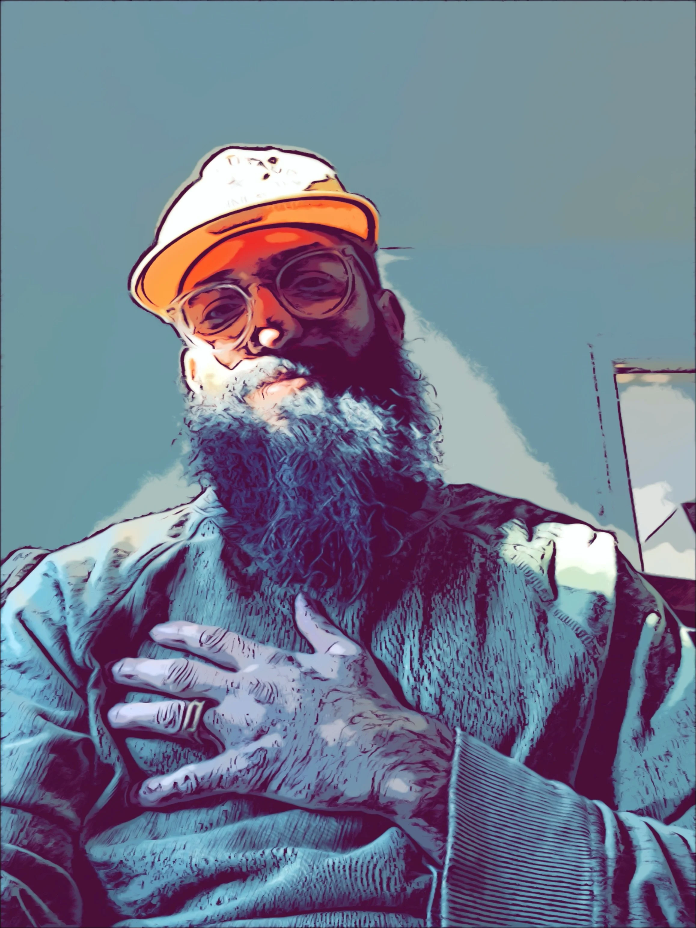 A person with a beard wearing glasses, a baseball cap, and a jacket, taking a selfie outdoors against a clear blue sky.