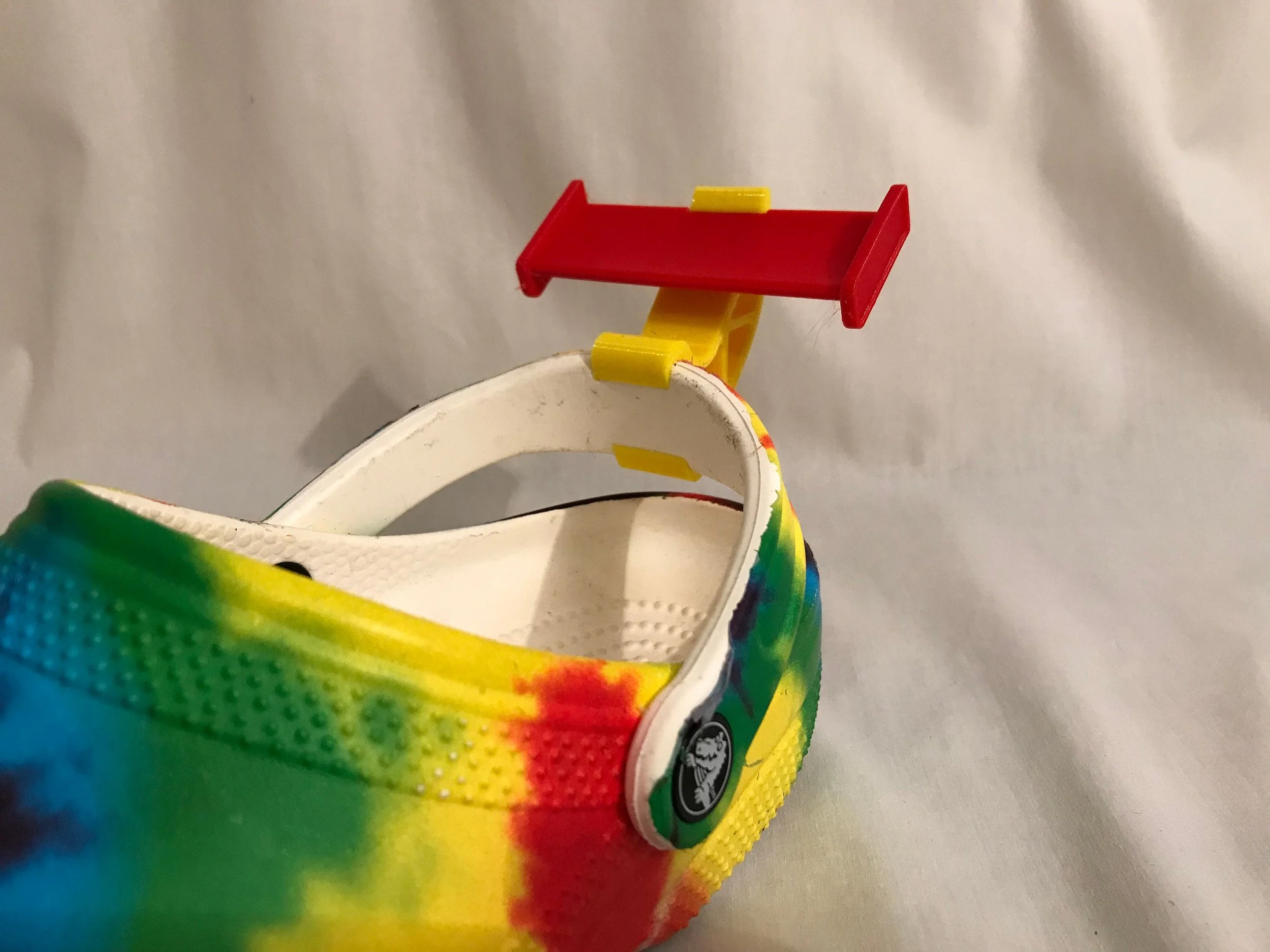 Red spoiler on the heel of a tie-dye Croc