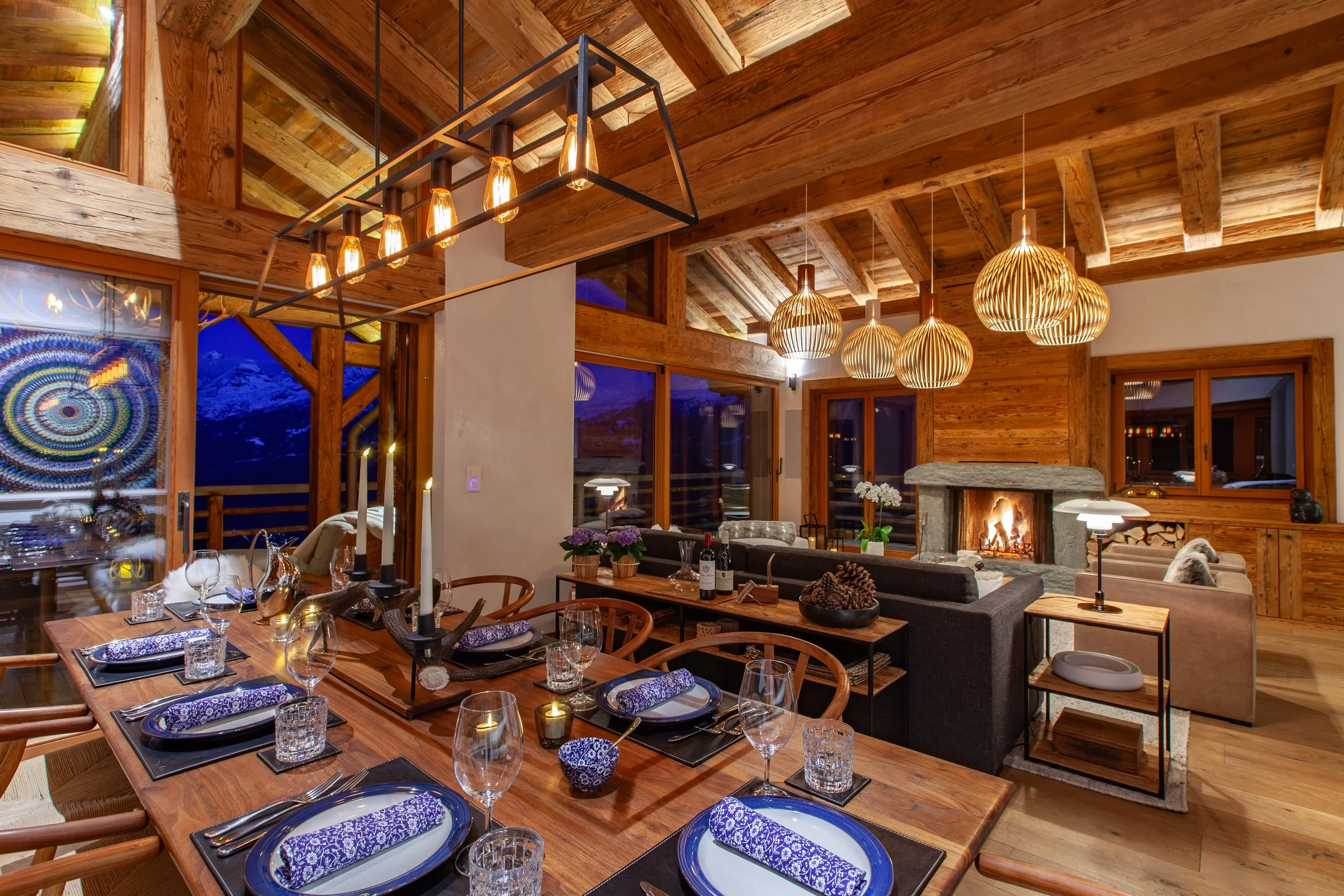 Evening dining table with Big Mountain Antlers antler candelabra, living room and roaring fire beyond, Chalet la Vigne Verbier Switzerland