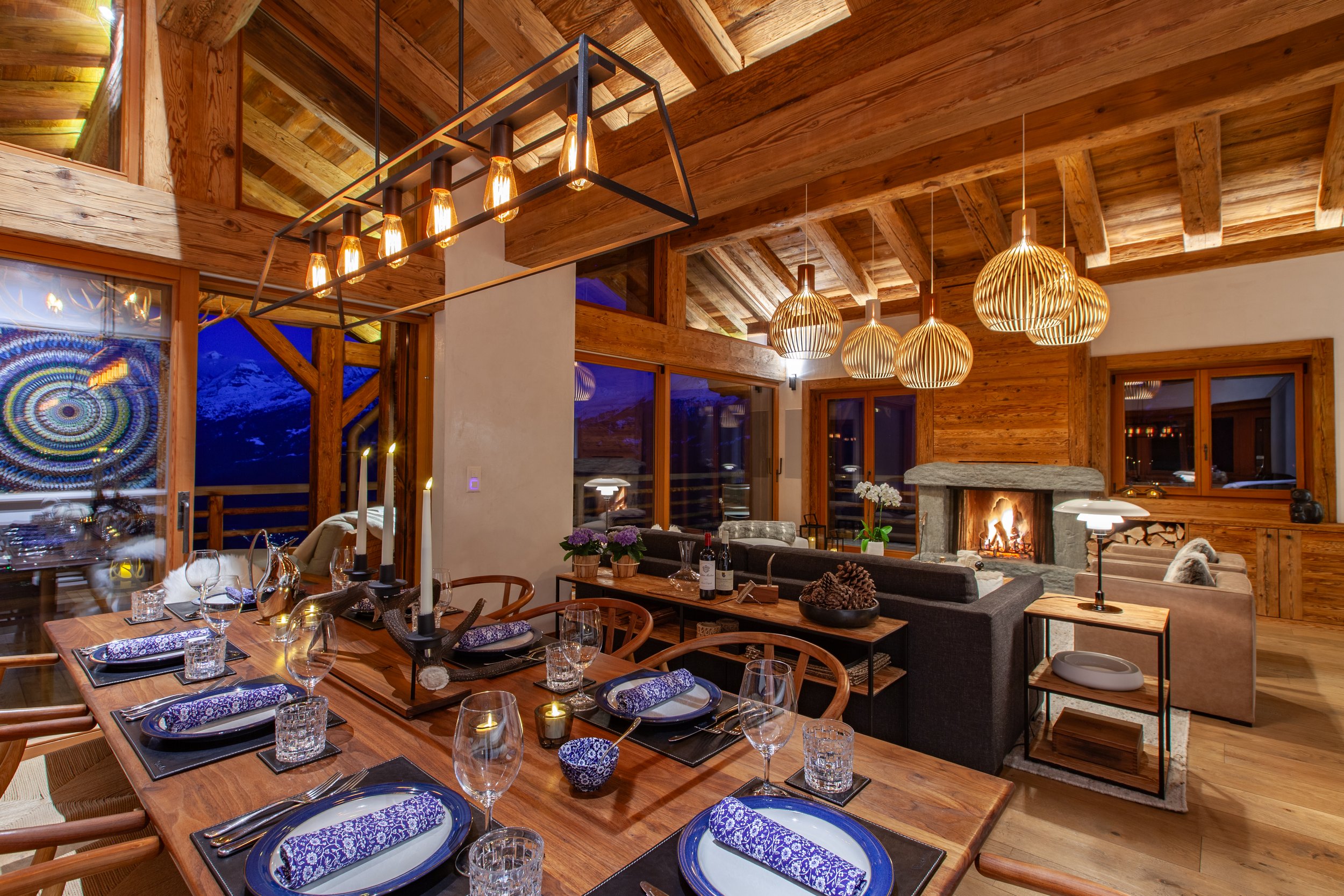 Set dining table at dusk with Carl Hansen chairs, Secto Design lighting and roaring fire, Chalet la Vigne Verbier Switzerland