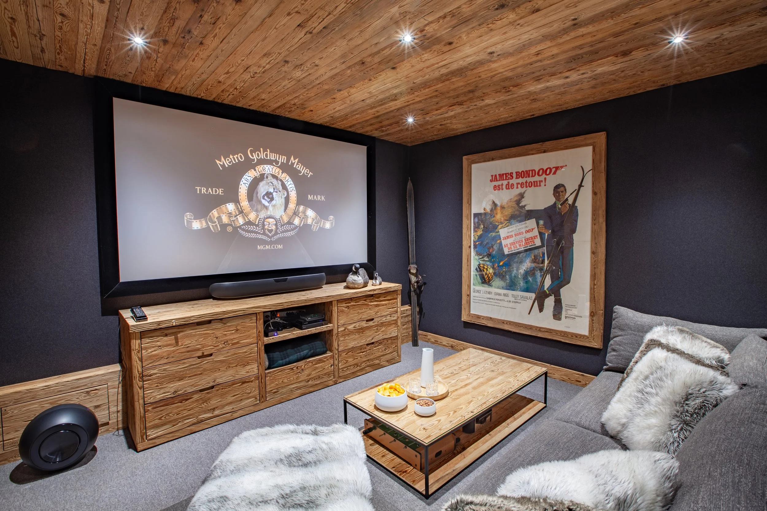 Private cinema with Meridiani sofa, projector, large screen, fur throws and James Bond poster, Chalet la Vigne Verbier luxury ski chalet Switzerland