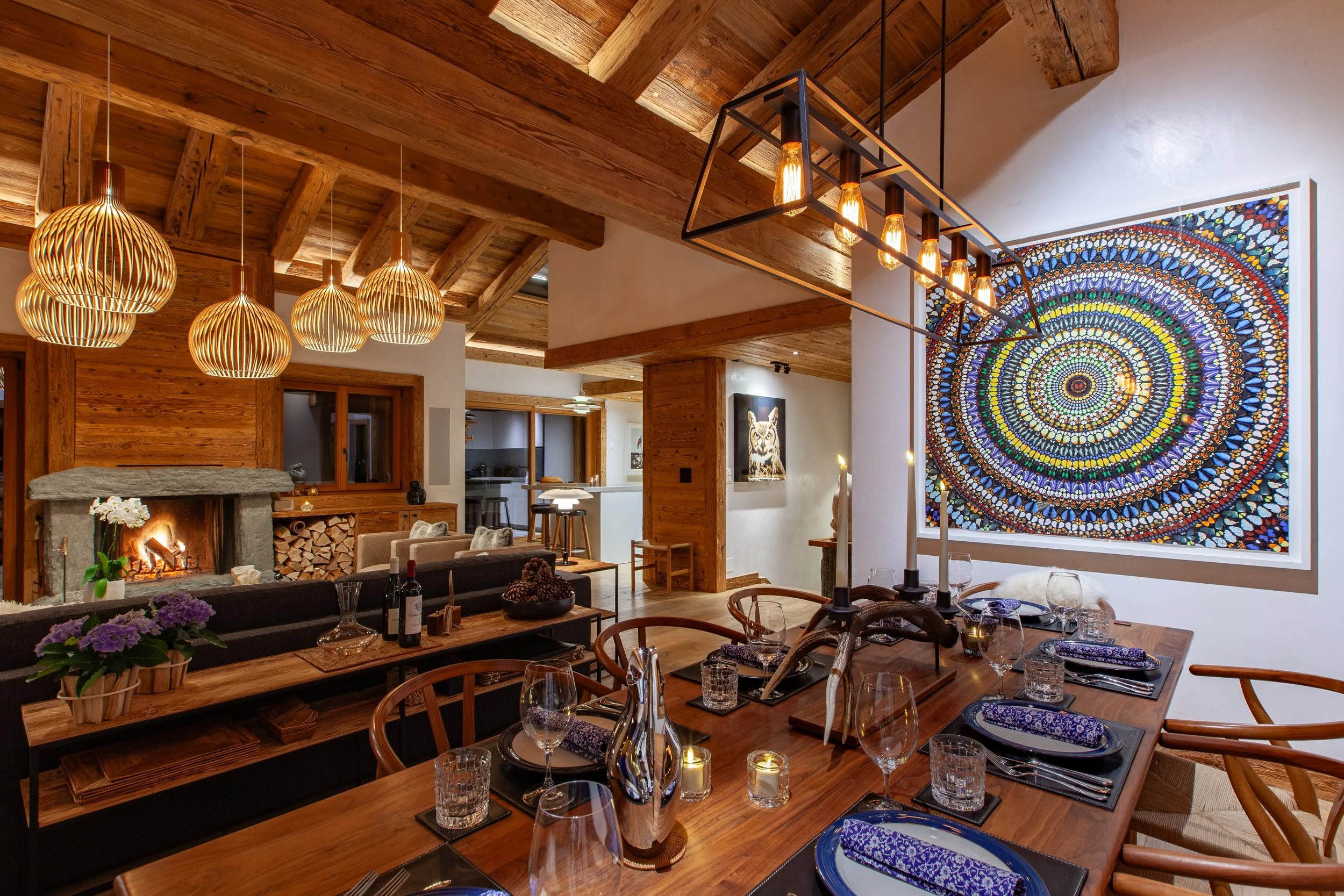Evening dining table with Secto Design lighting, contemporary art and roaring fire beyond, Chalet la Vigne Verbier luxury ski chalet Switzerland