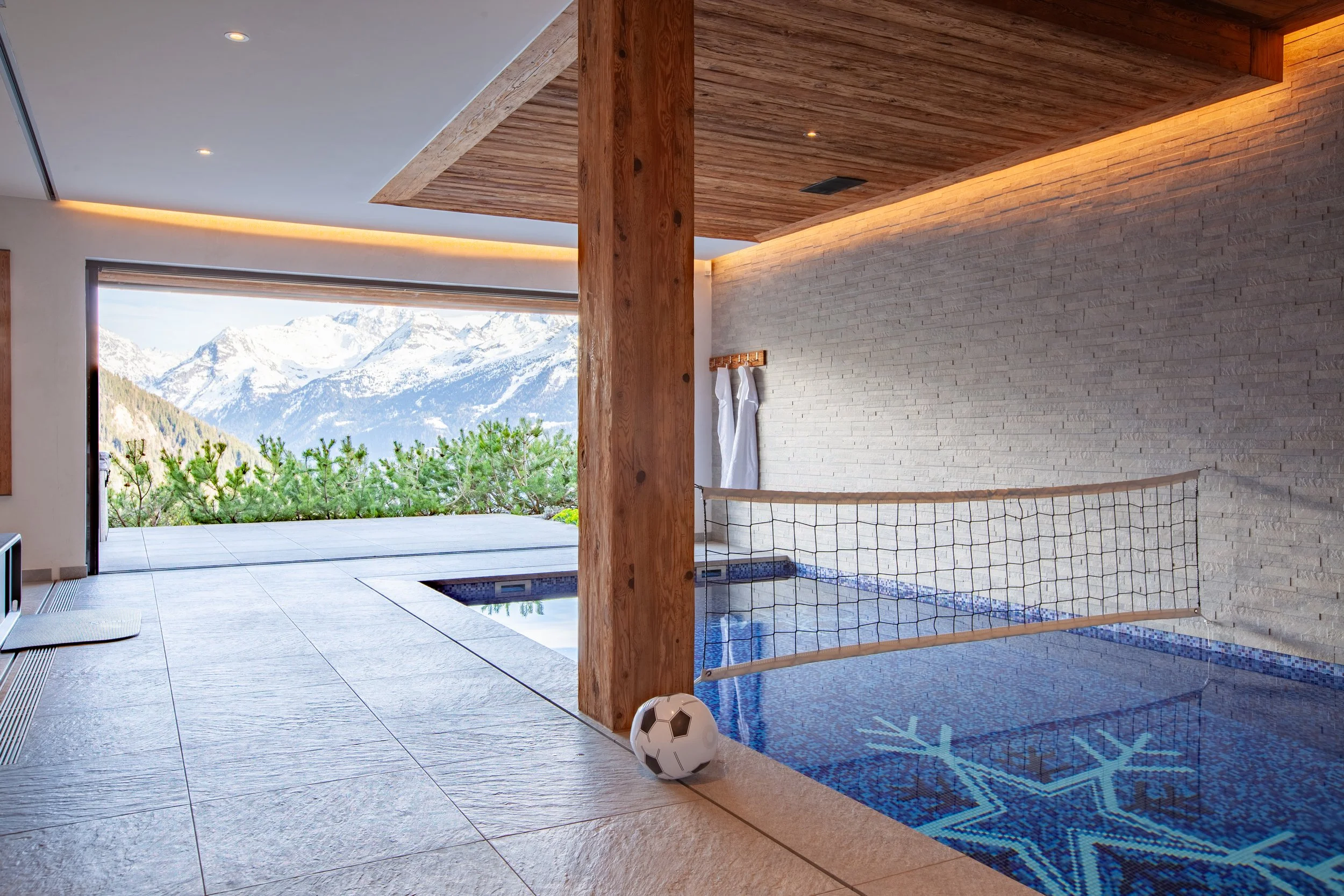Indoor swimming pool with Sicis mosaic snowflake tiles, panoramic Alpine views and pool volleyball net, Chalet la Vigne Verbier luxury ski chalet Switzerland