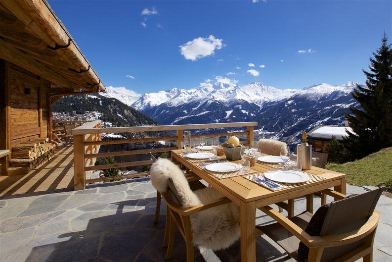 Al fresco dining on the sunny terrace with panoramic Alpine mountain views, Chalet la Vigne Verbier Switzerland