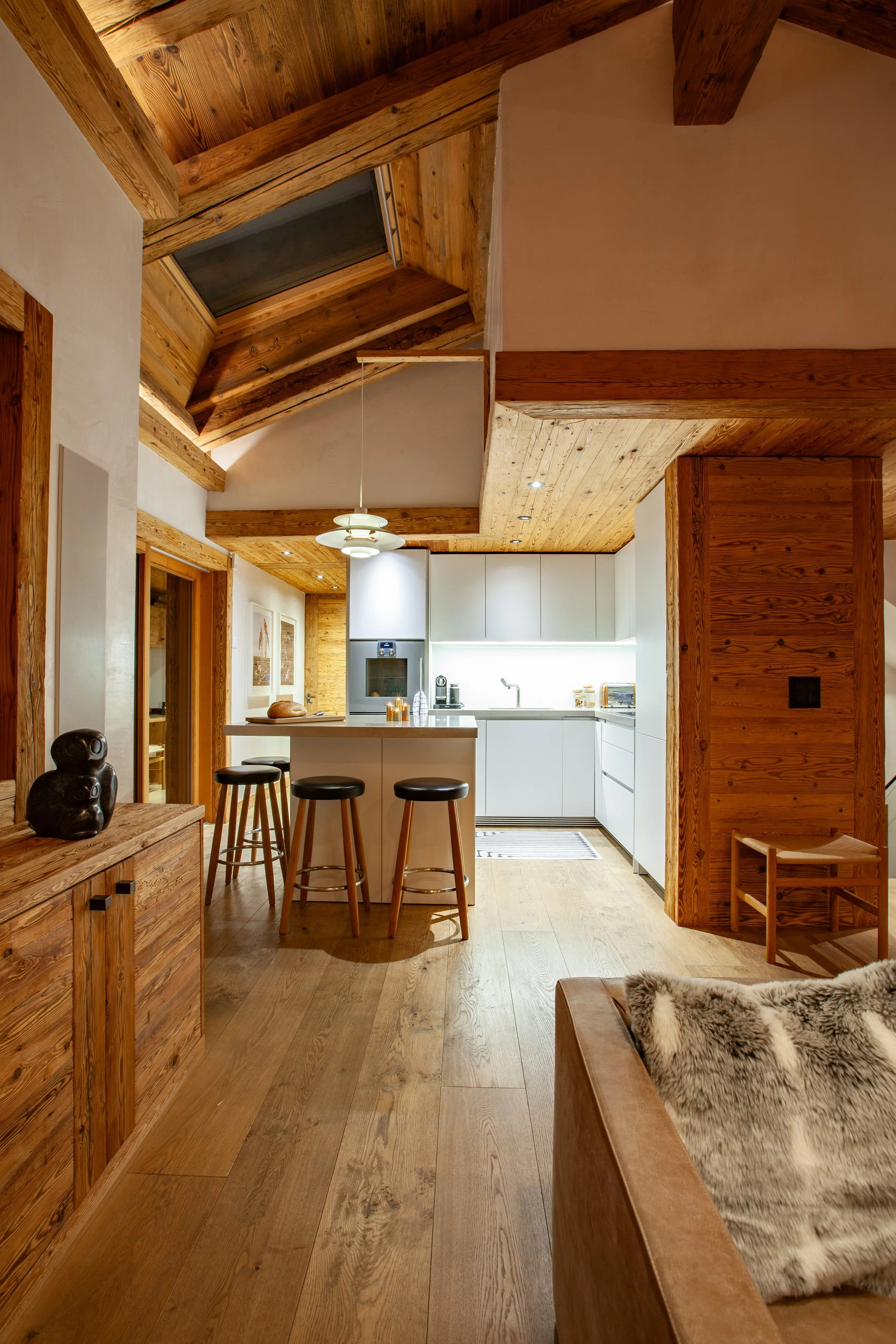 Bulthaup kitchen at evening with rustic Swiss wooden interior and Inuit sculpture, Chalet la Vigne Verbier Switzerland