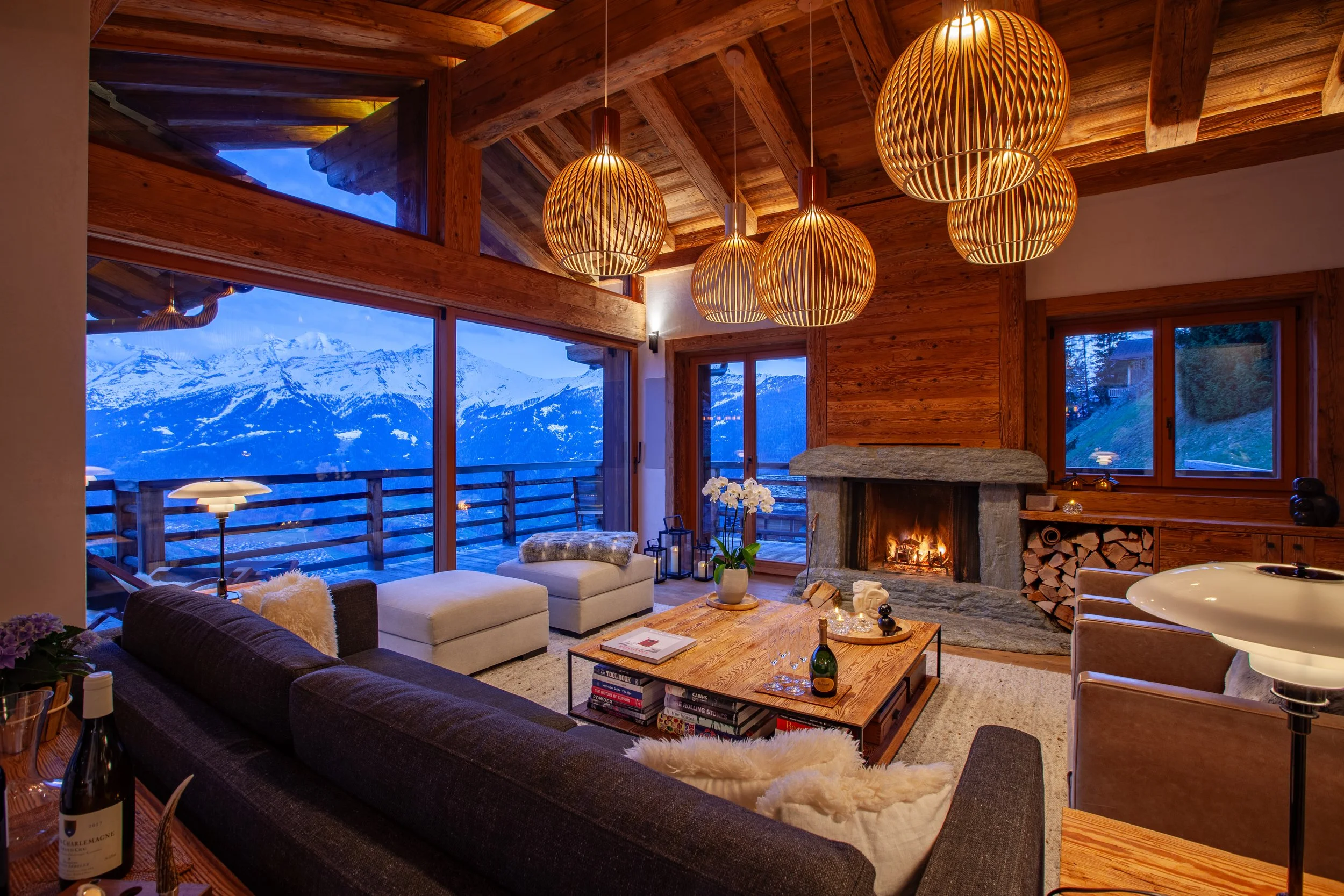 Living room at dusk with Meridiani furniture, Louis Poulsen lighting and panoramic Alpine mountain views, Chalet la Vigne Verbier Switzerland