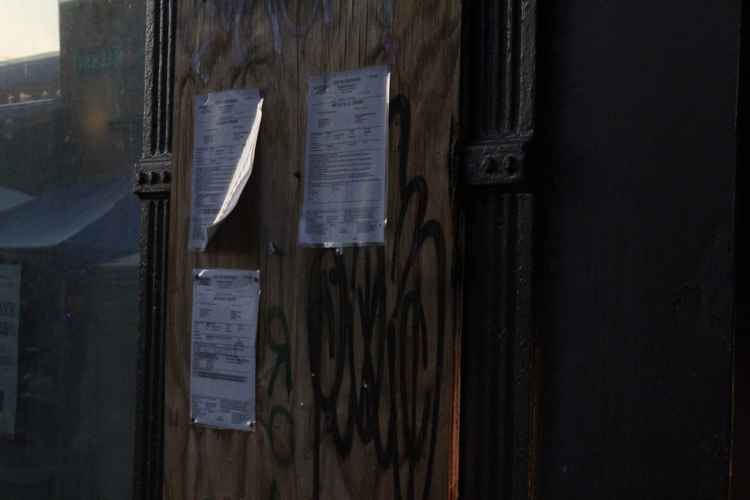Multiple parking permits attached to a wooden surface, with some graffiti tags in the background.