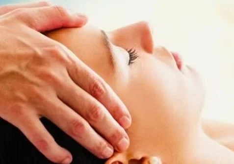 A person receiving a head massage or scalp massage with their eyes closed.