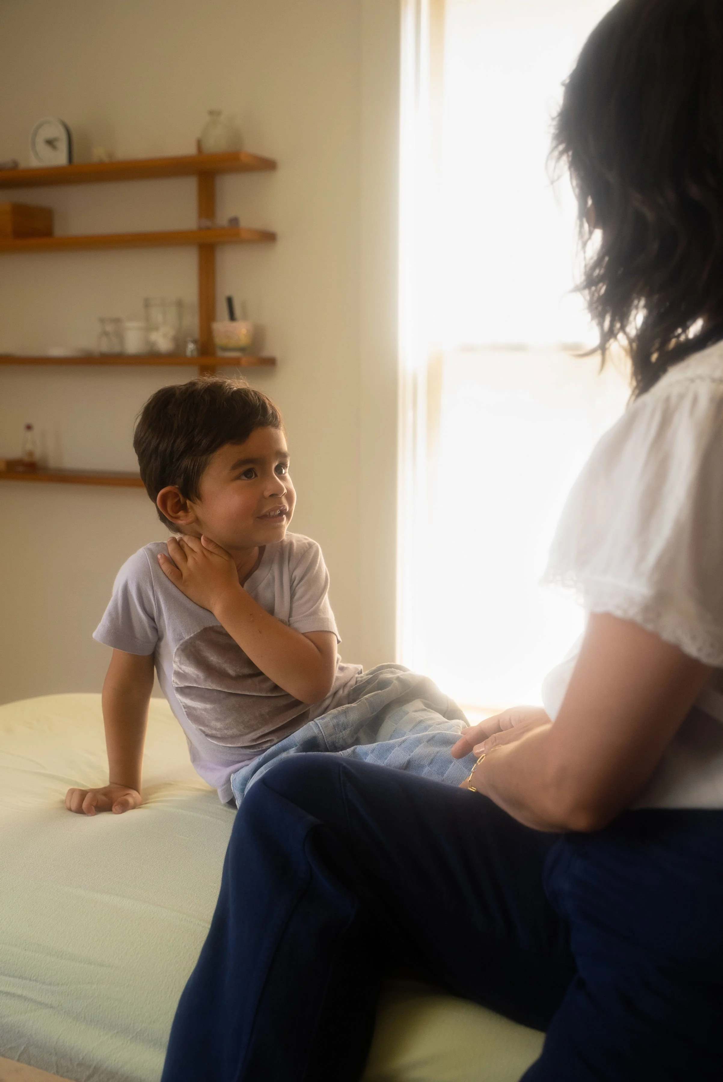 A young boy sitting on a treatment bed receiving pediatric integrative care