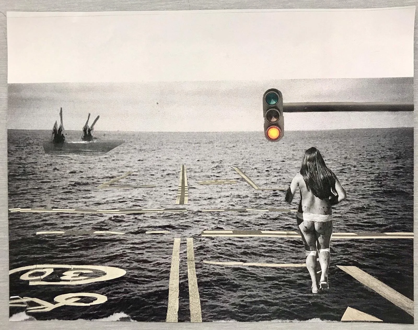 Black and white surreal image of a woman with long hair walking on a road that leads into the ocean, with a traffic light overhead and two metal structures in the water. The road has markings including a bicycle lane and a no parking sign.