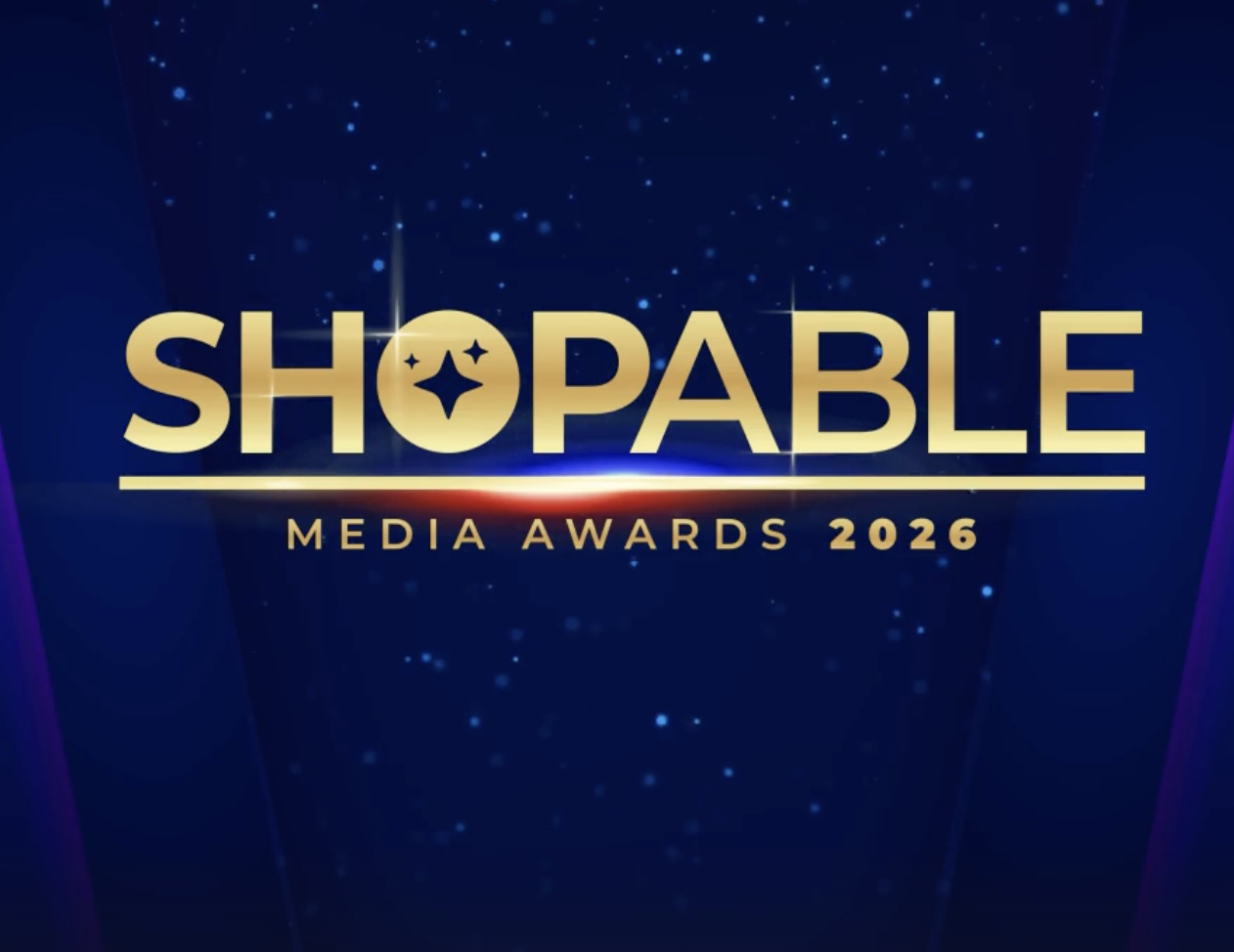 Logo for the Shopable Media Awards 2026, featuring gold-colored text on a dark blue background with star-like accents.