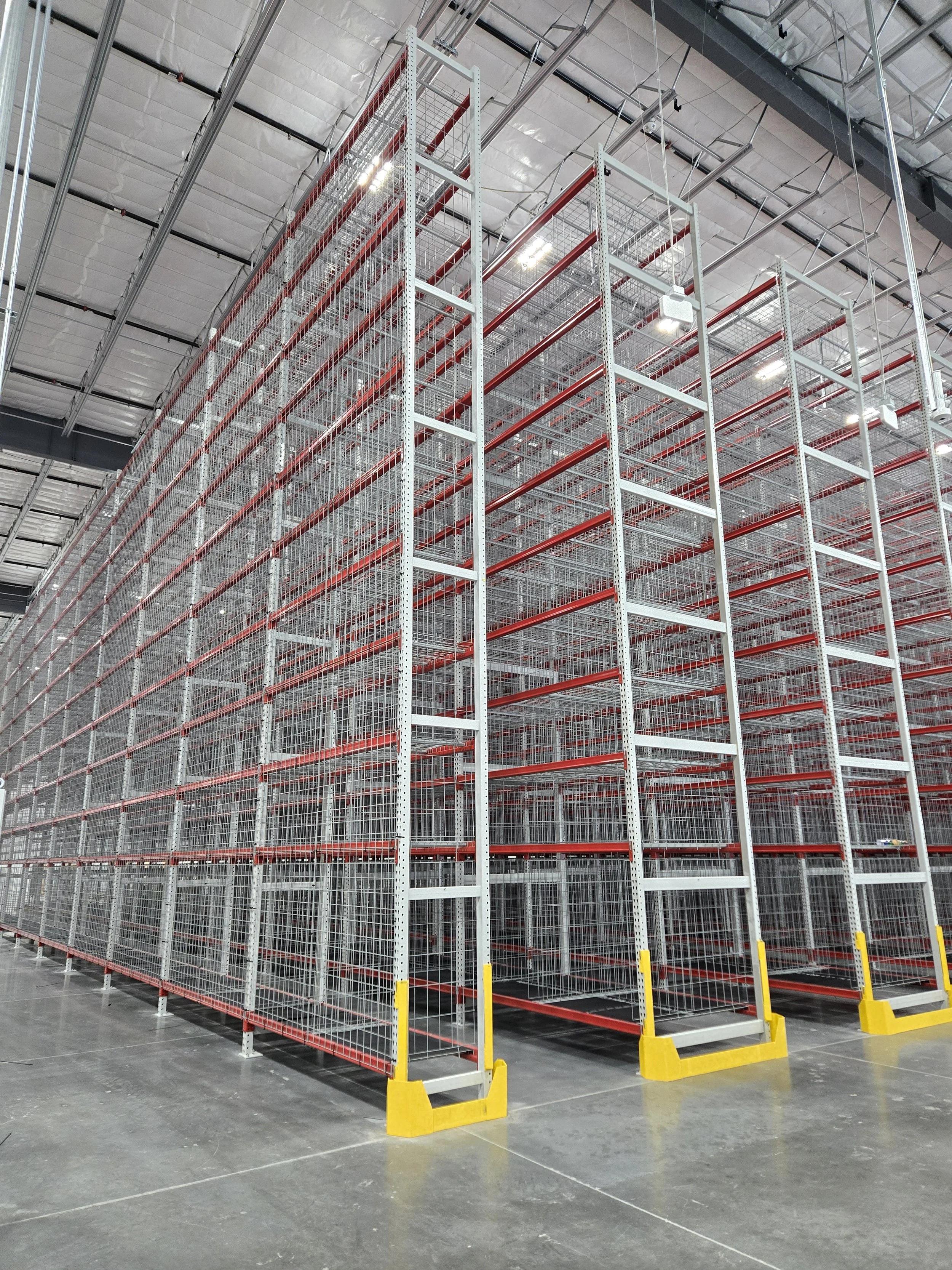 Metal retail shelving units inside a warehouse with a concrete floor and ceiling panels