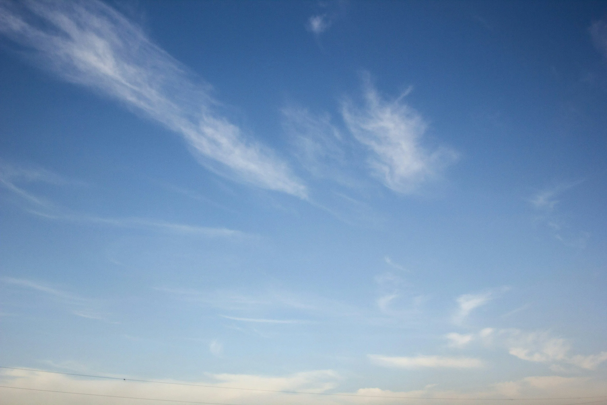 Clear blue sky with a few wispy clouds and a faint moon visible.