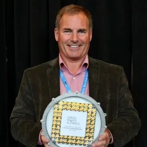 Man in blazer holding an award with a framed message at an event