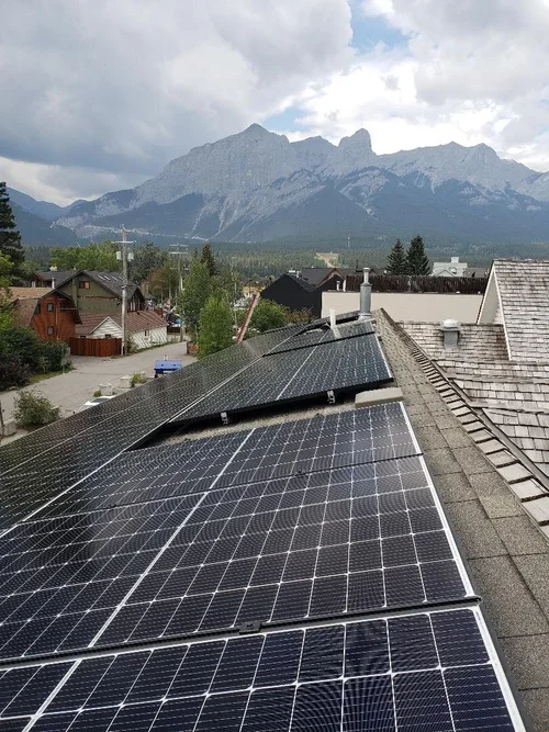 Solar panels installed on a rooftop with mountainous landscape in the background.