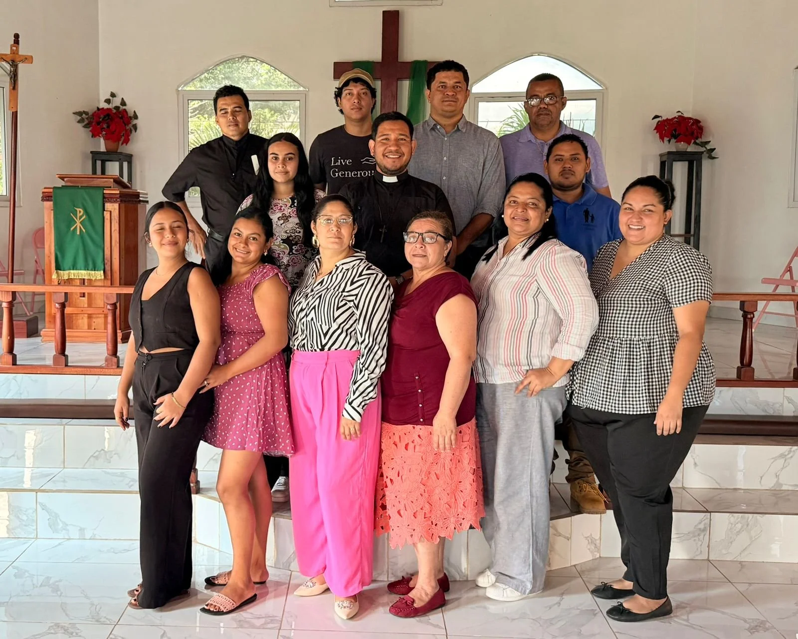 Grupo de personas en la iglesia, con un altar al fondo y una cruz en la pared detrás, posando para la foto.