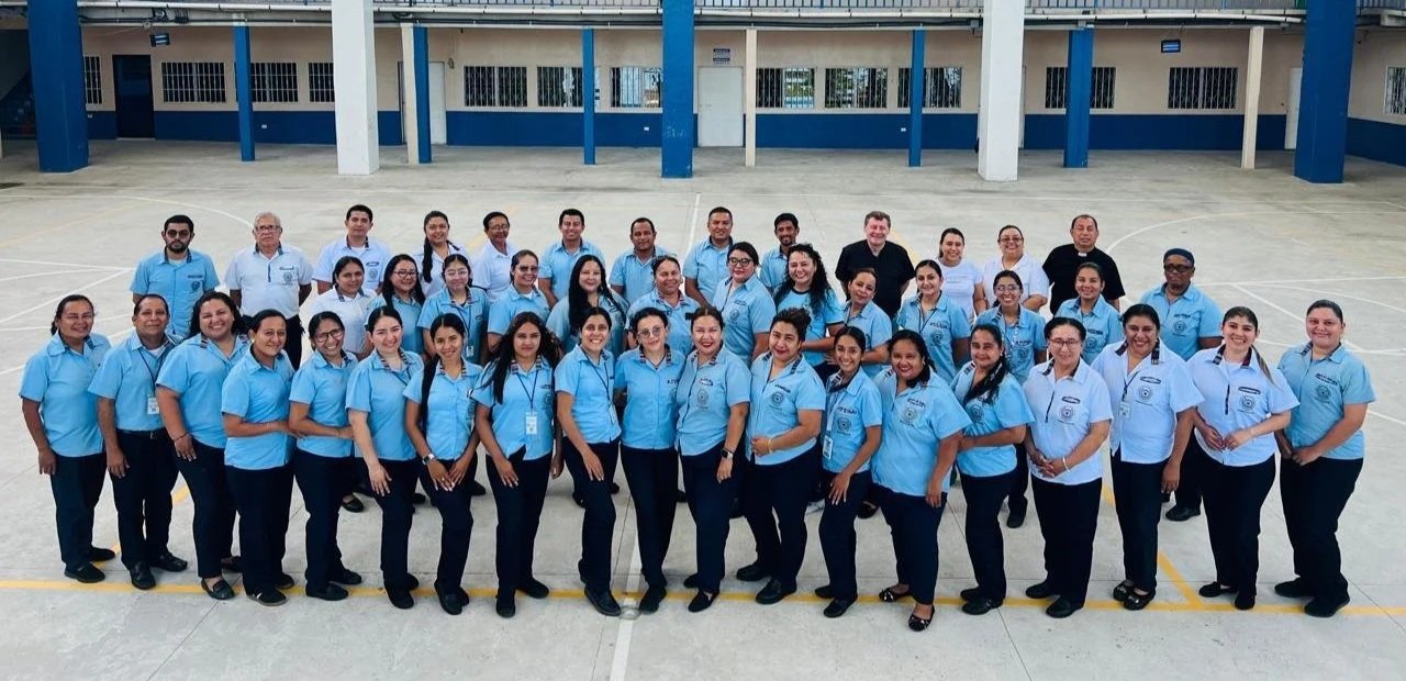 Grupo de personas en uniforme escolar posando en un patio escolar.