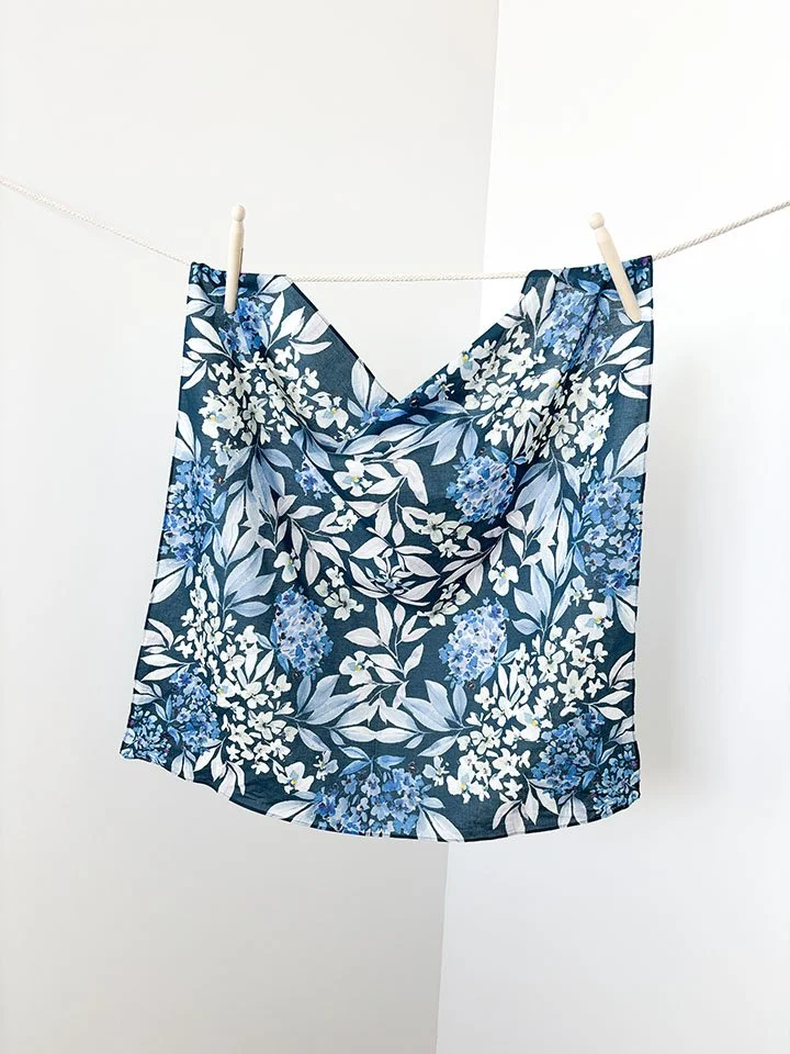 A floral patterned fabric hanging on a clothesline with clothespins.