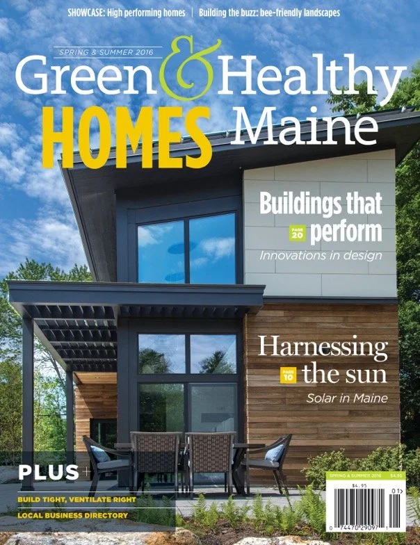 Cover of Green & Healthy Homes Maine magazine featuring a modern house with wooden and blue exterior finishes, large windows, and outdoor seating amid greenery, with headlines about building performance, sun harnessing, and eco-friendly design.