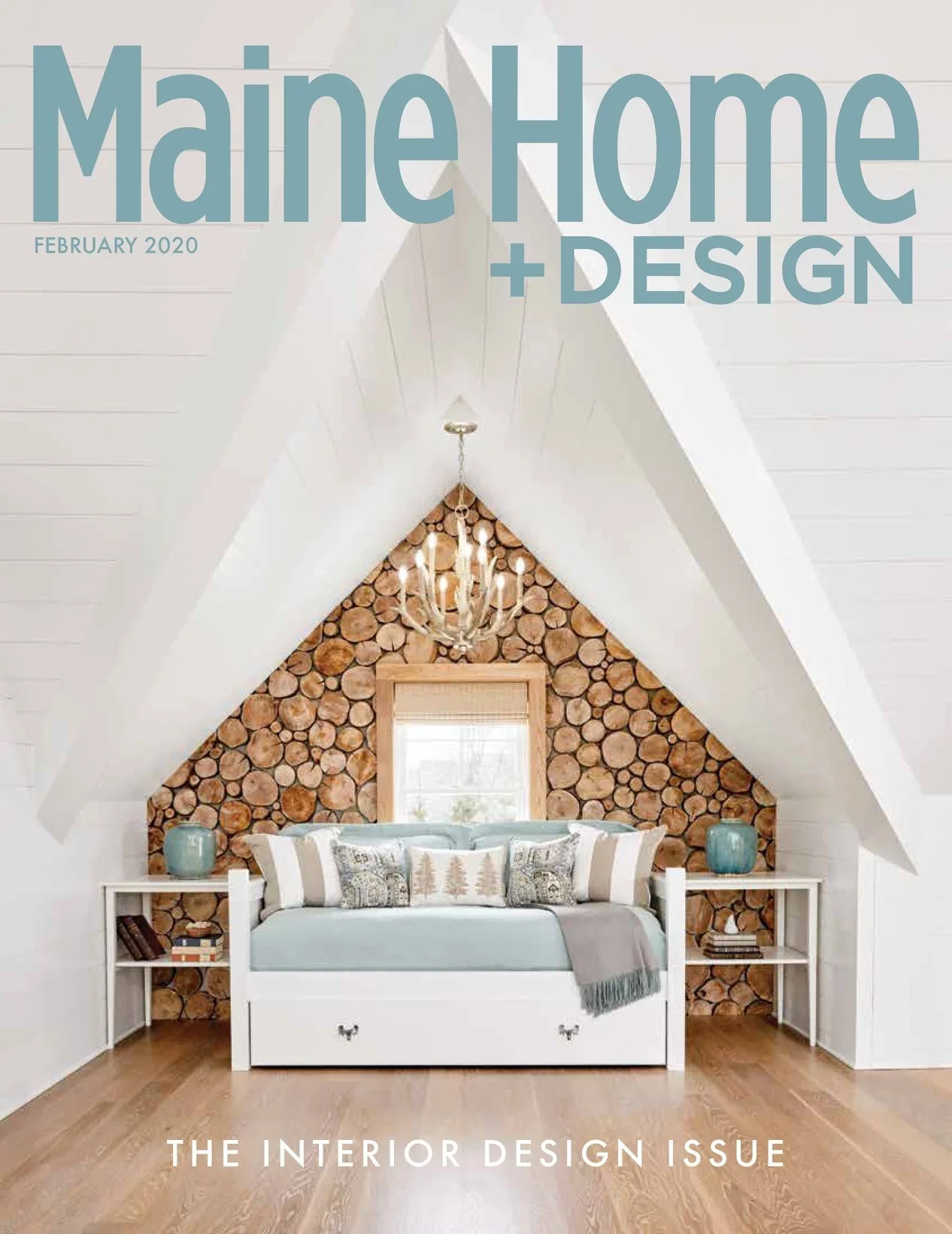 A bedroom with white walls and slanted ceilings, featuring a cozy bed with a light blue blanket, decorative pillows, and twin nightstands on each side. Above the bed, a wall with stacked logs creates a natural accent, and a chandelier hangs from the 