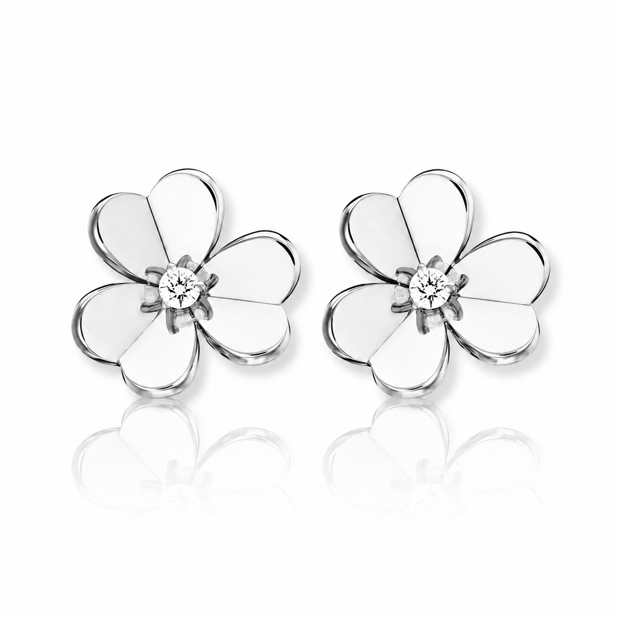 Silver flower-shaped earrings with a central gemstone reflected on a white surface.