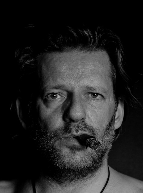 Black and white photo of a man with a beard smoking a cigar