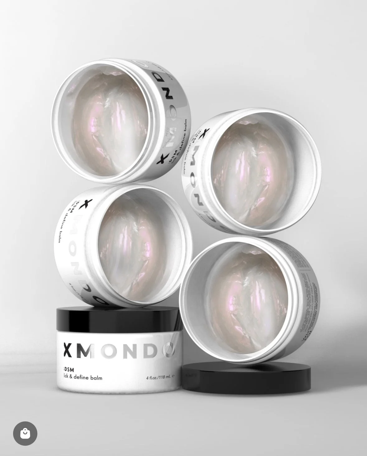 Four white containers labeled 'XMONDO' with iridescent balm inside, arranged on black circular bases on a white background.