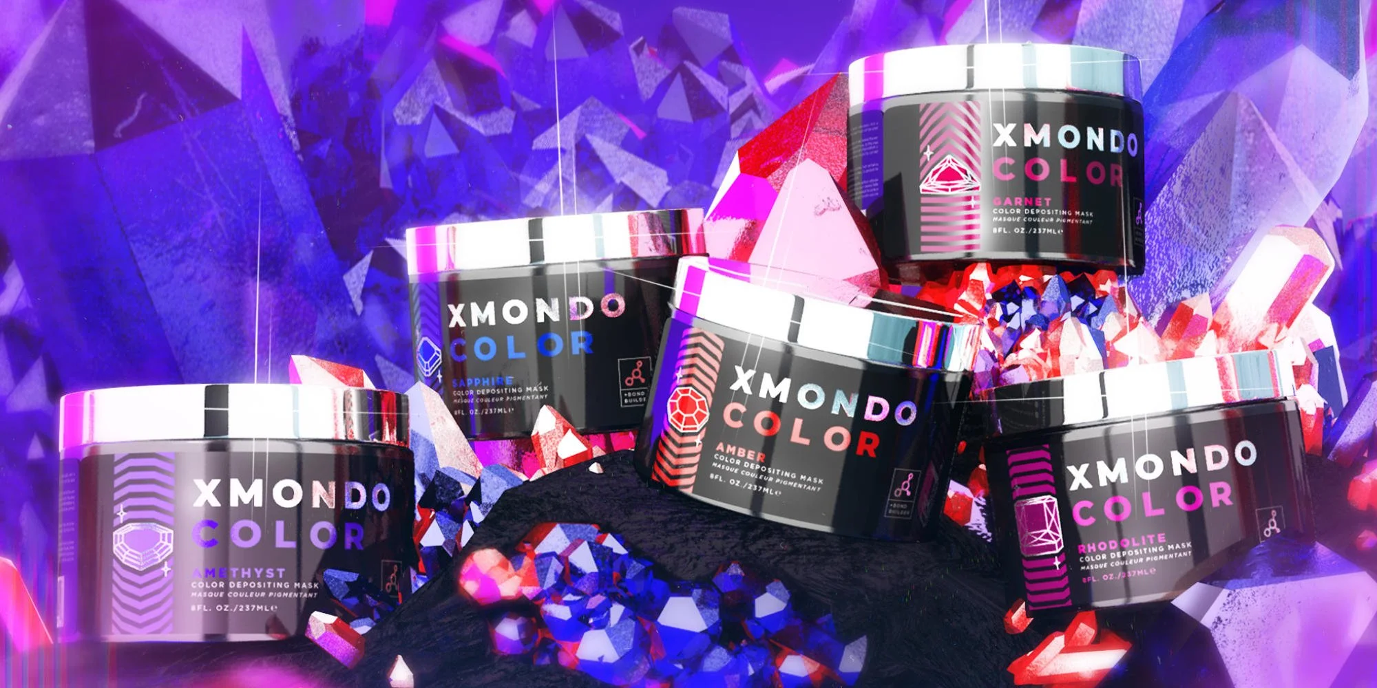 Several containers of XMONDO COLOR face masks in various shades, surrounded by colorful crystals and geometric shapes, with a vibrant purple and pink abstract background.