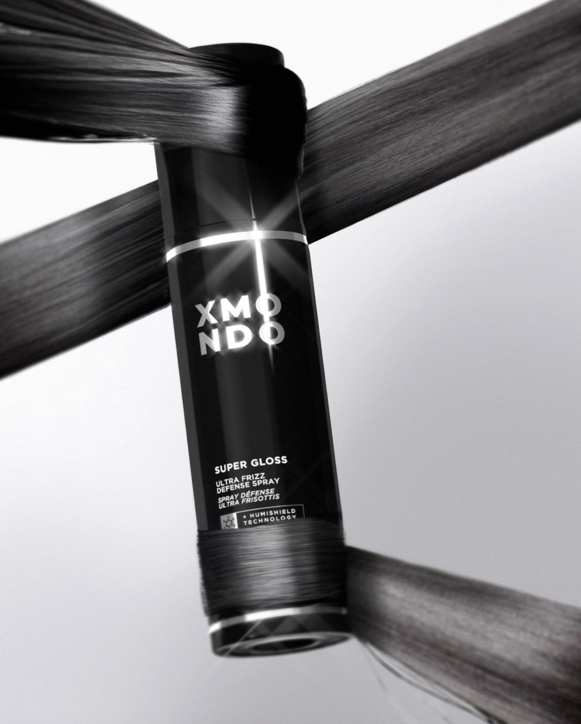 A black spray can labeled 'Super Gloss Ultra Frizz Defense Spray' with 'Humishield Technology' is balanced between two wooden planks, one above and one below.