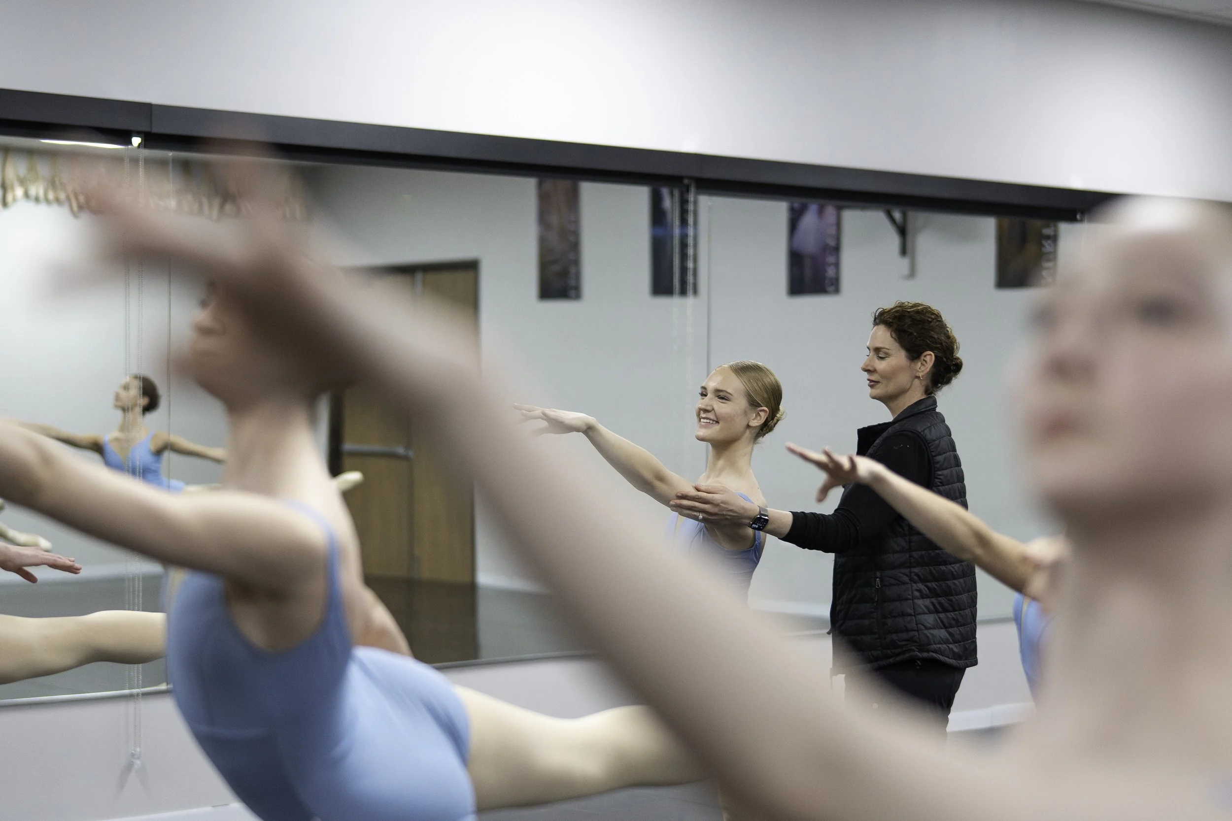 Ballet class with young dancers practicing stretches and ballet moves in a dance studio, supervised by instructor
