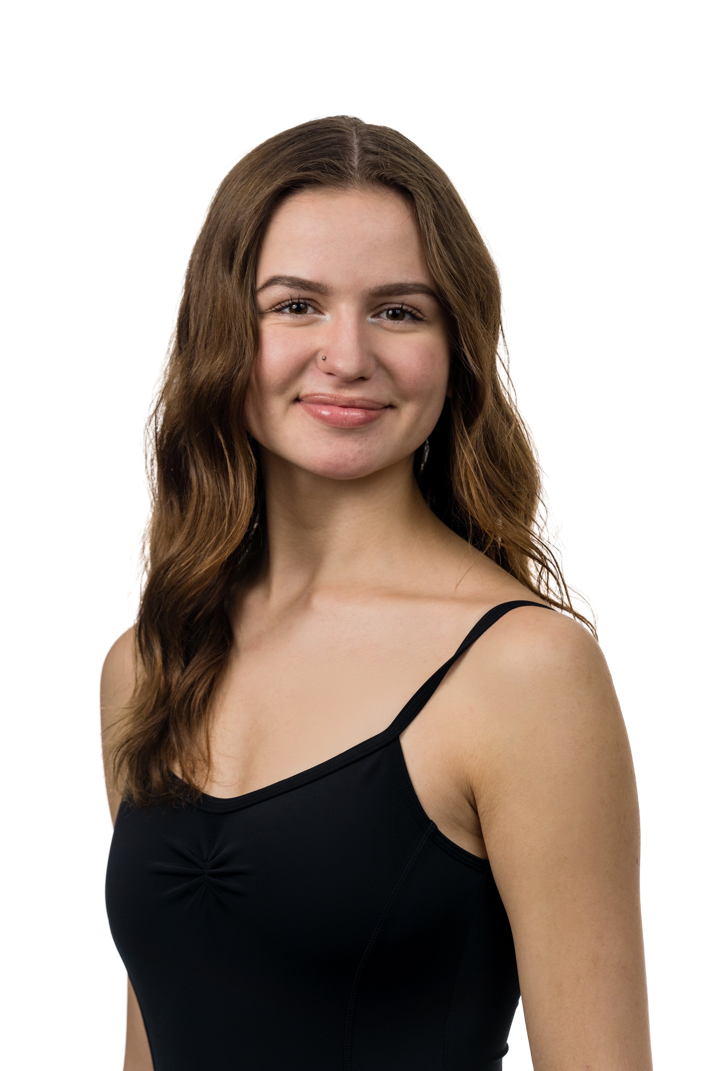 Portrait of a young woman with long wavy brown hair, wearing a black spaghetti strap top, smiling at the camera against a plain white background.