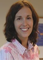 MaryBeth Toran, MD wearing a pink striped shirt, standing indoors with blurred background.